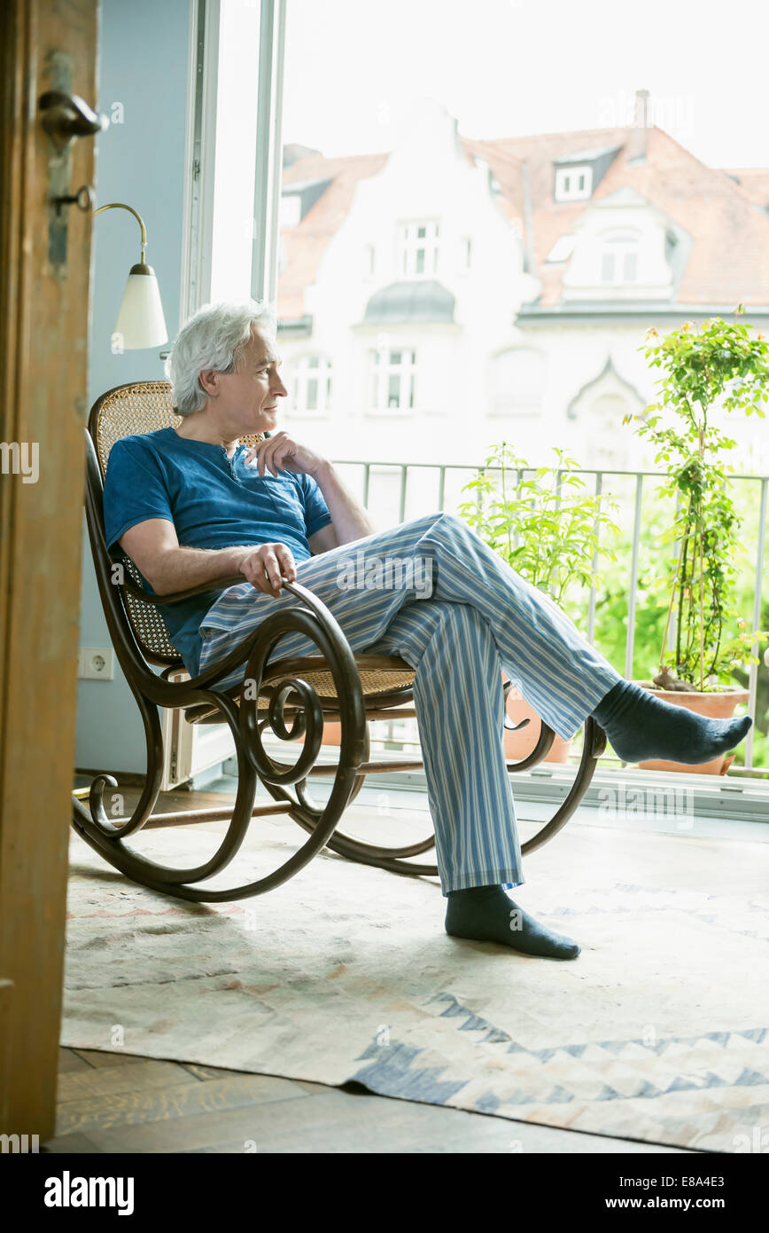 Mature man sitting in rocking chair, looking away Stock Photo Alamy