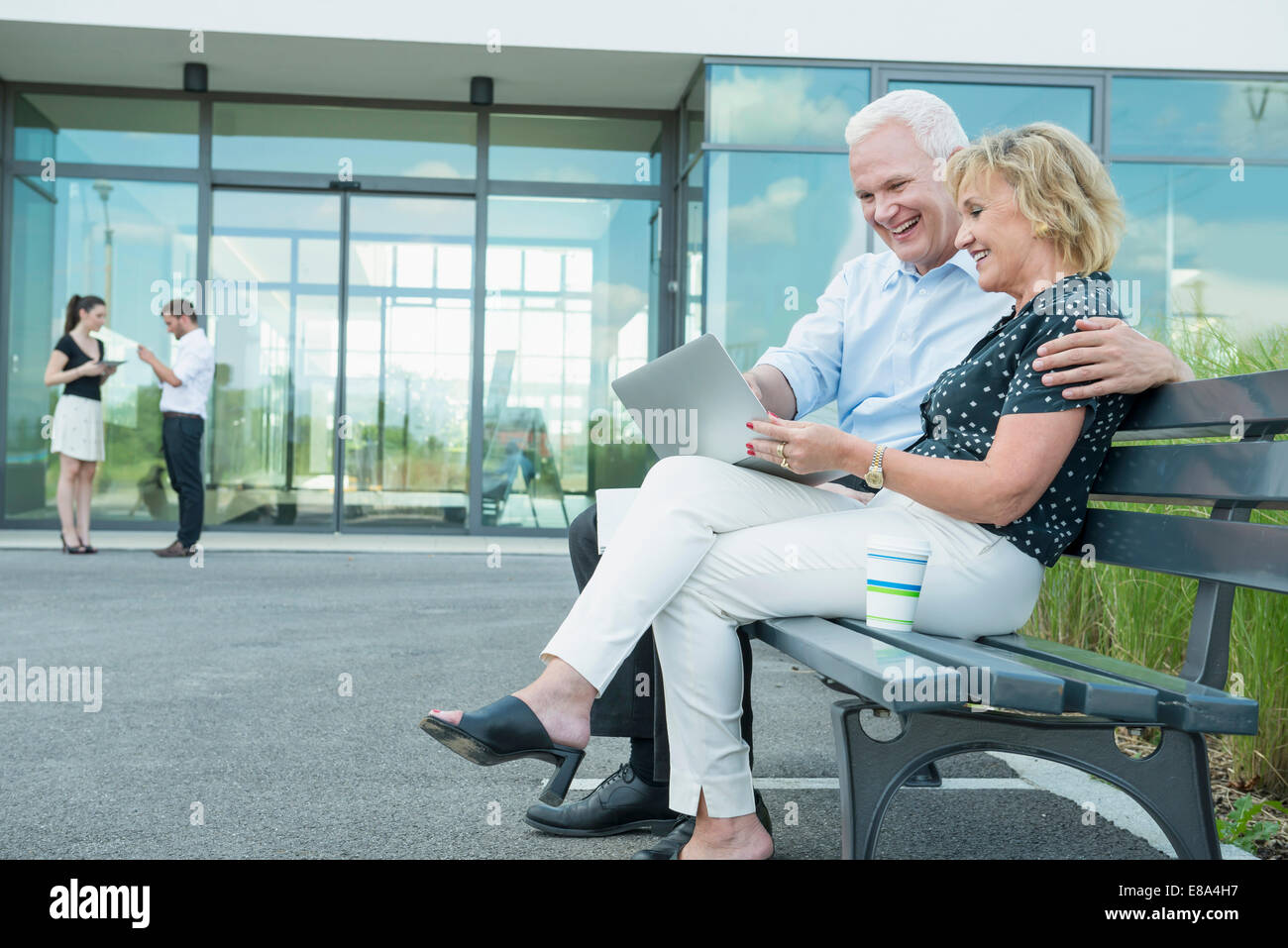 couple sitting on a bench, using tablet computer Stock Photo - Alamy
