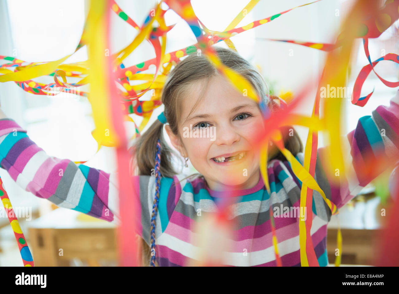 Portrait of girl with blowout paper streamer at birthday party, smiling Stock Photo