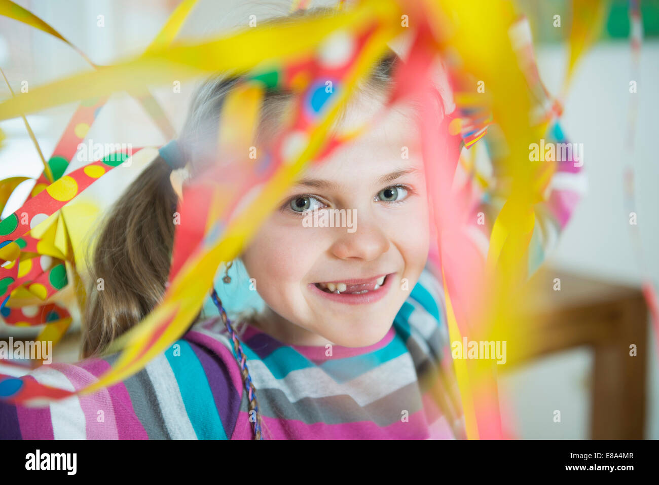 Portrait of girl with blowout paper streamer at birthday party, smiling ...