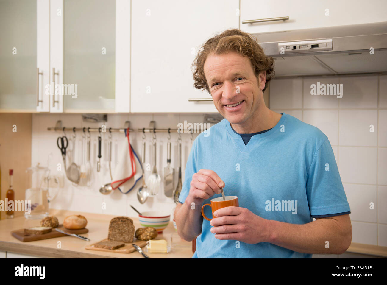 Smiling man with cup of coffee in kitchen Stock Photo