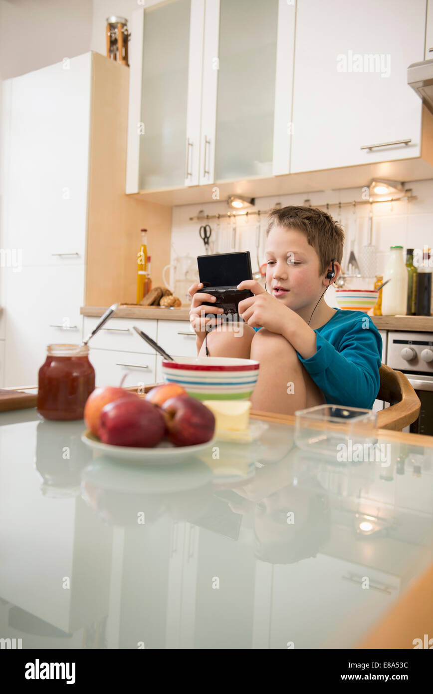 Boy playing video game in kitchen Stock Photo