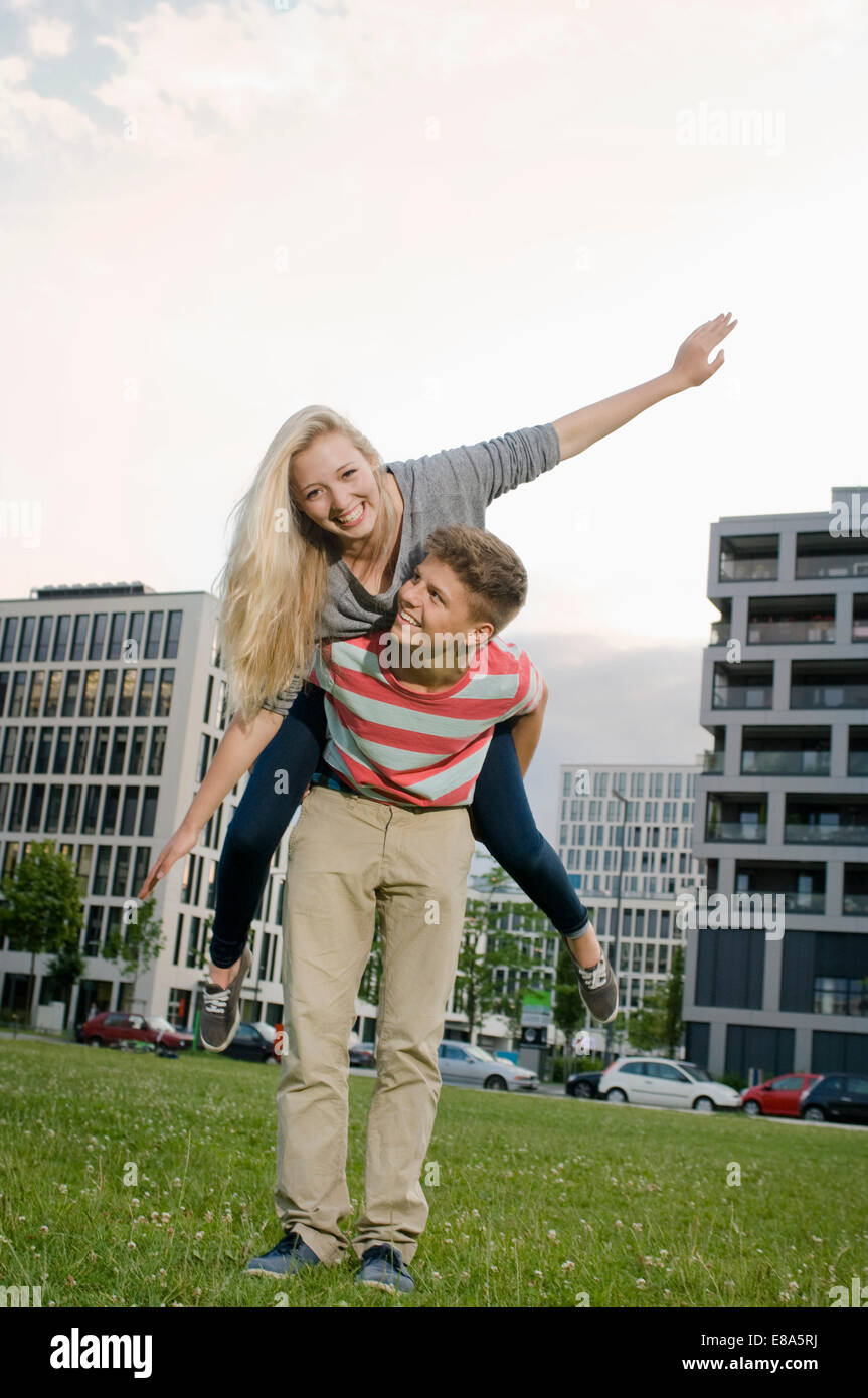 Teenage boy giving piggyback ride to teenage girl, smiling Stock Photo