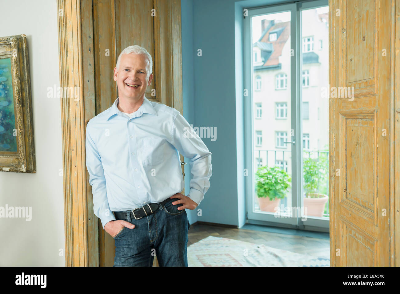 Portrait of mature man leaning against door, smiling Stock Photo