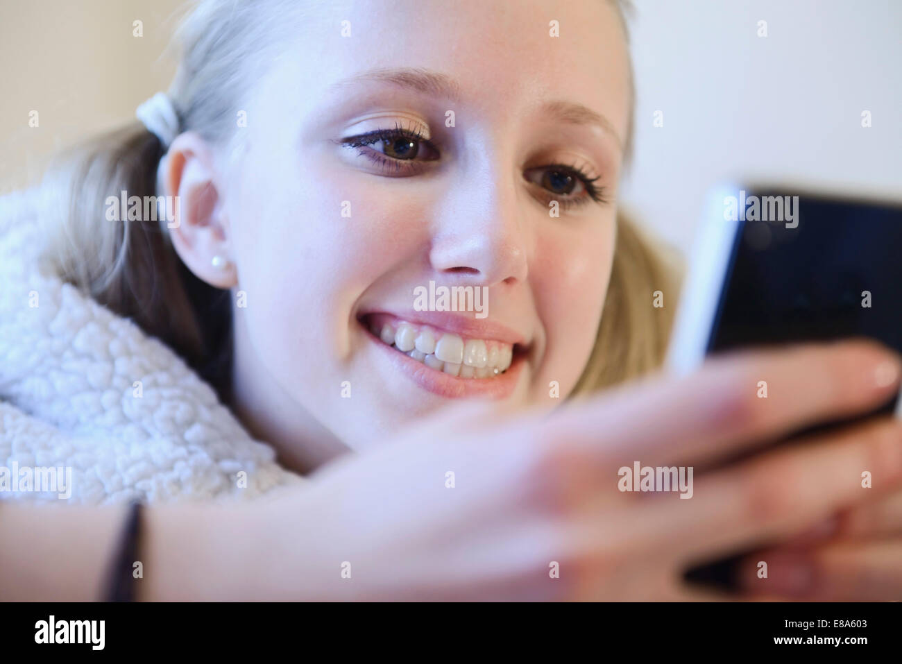 Teenage girl using smart phone on couch, smiling Stock Photo - Alamy