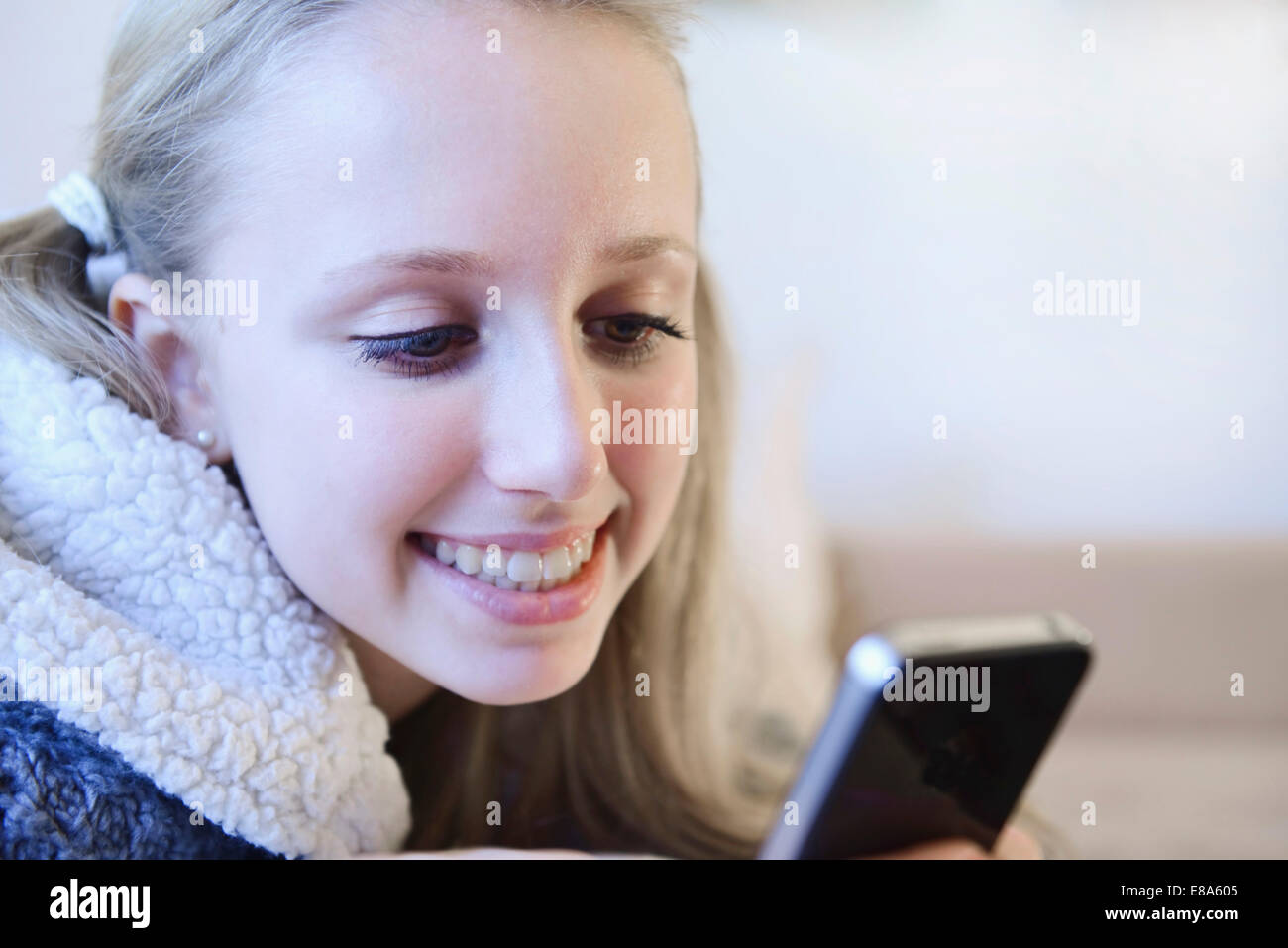 Teenage girl using smart phone on couch, smiling Stock Photo - Alamy