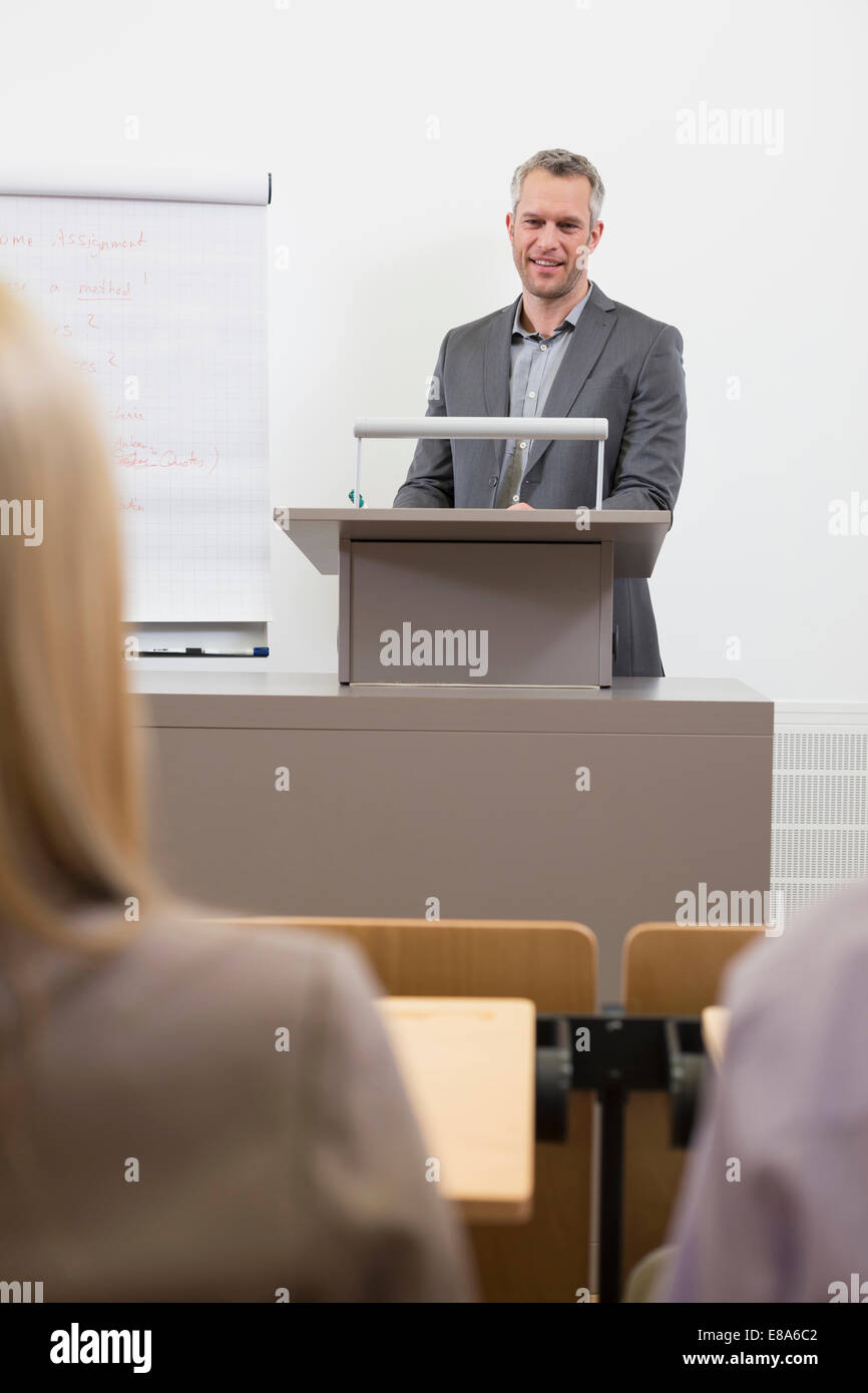 Businesspeople At Speakers Desk In Auditorium With Flip Chart