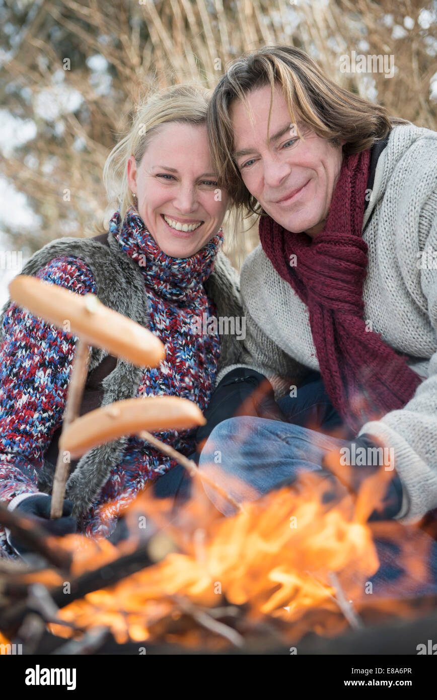 Couple barbecueing sausage on camp fire, Bavaria, Germany Stock Photo