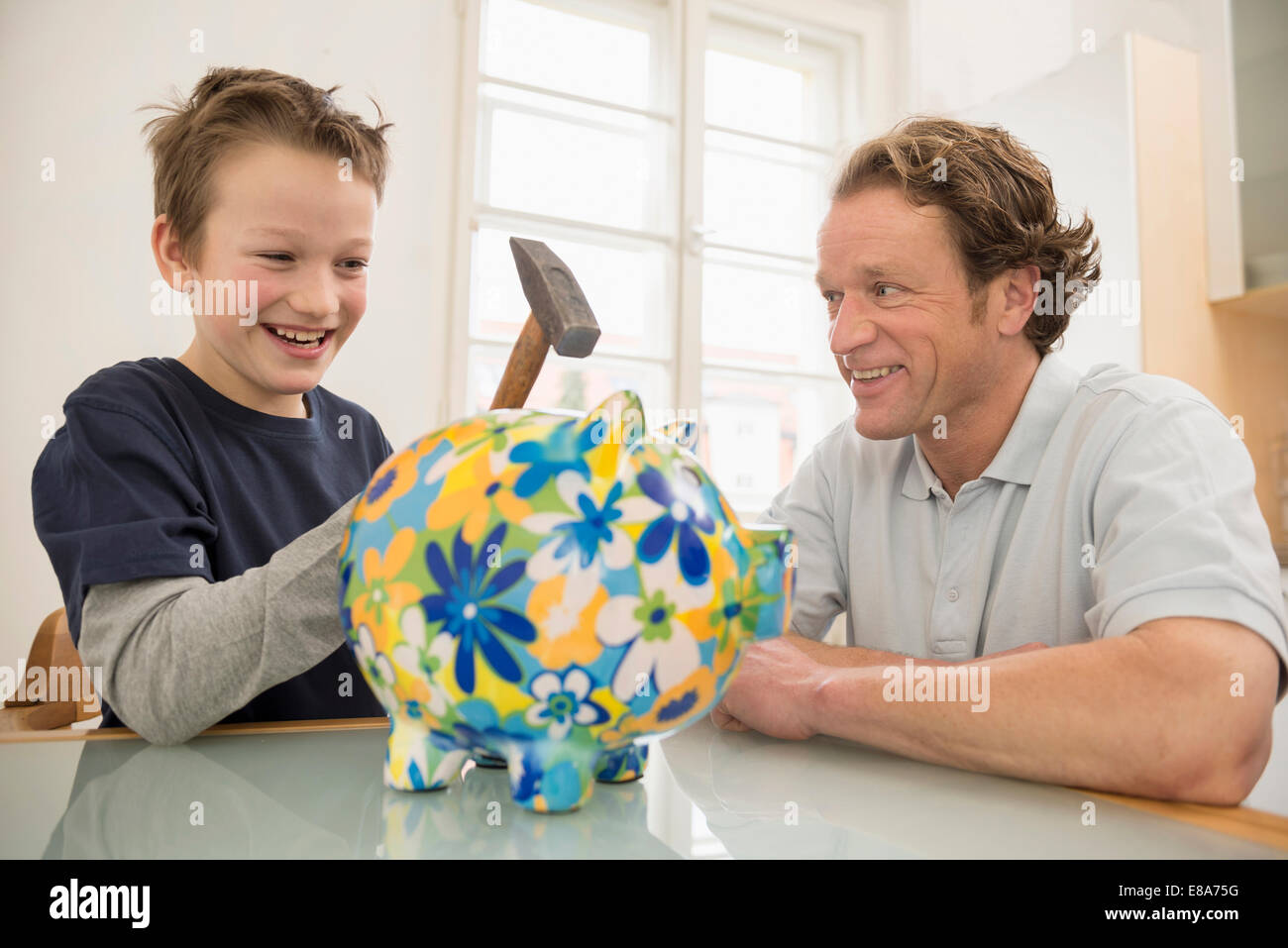 Father and son with piggy bank and hammer Stock Photo - Alamy