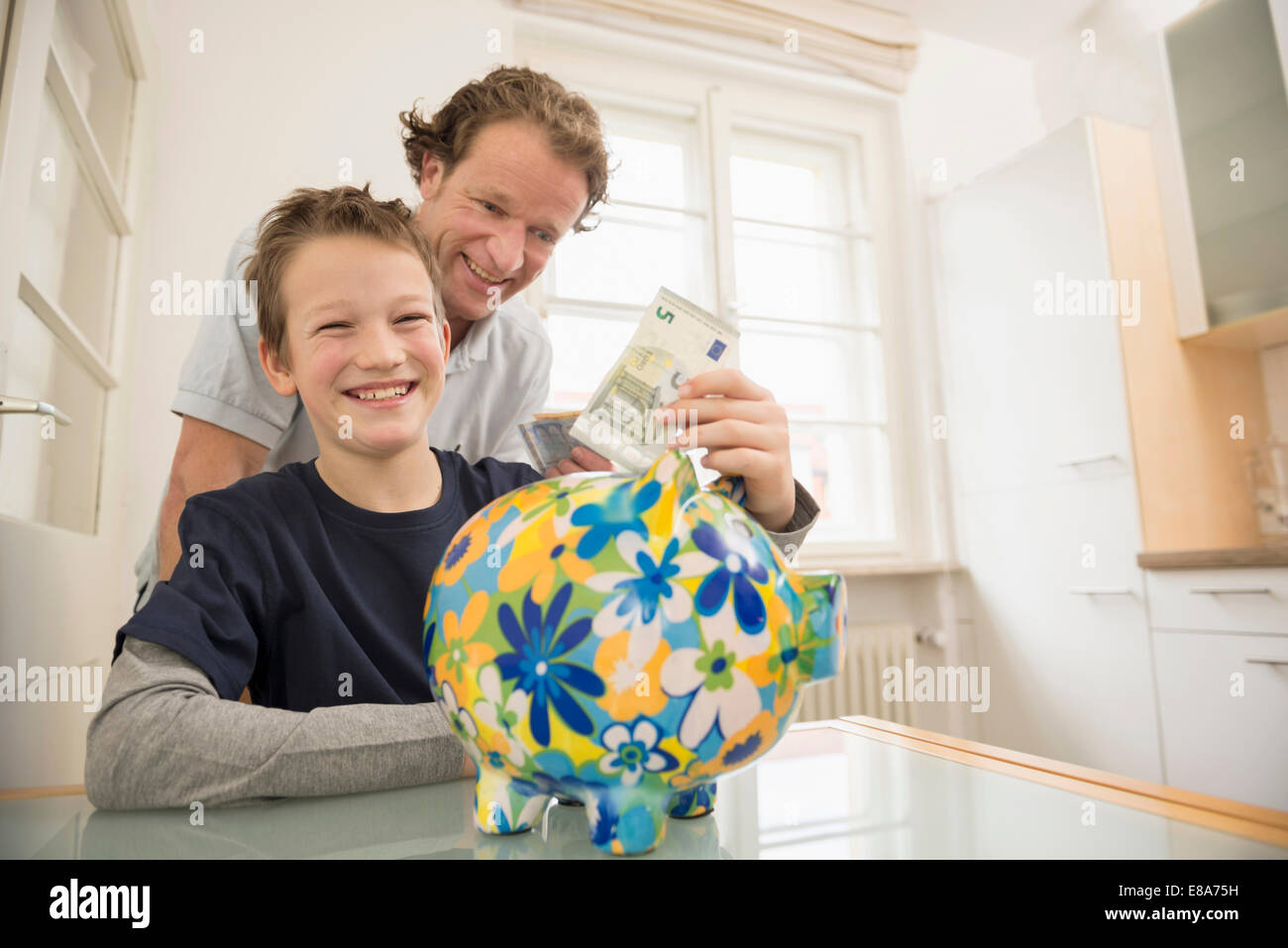 Father and son with piggy bank and 5 Euro note Stock Photo - Alamy