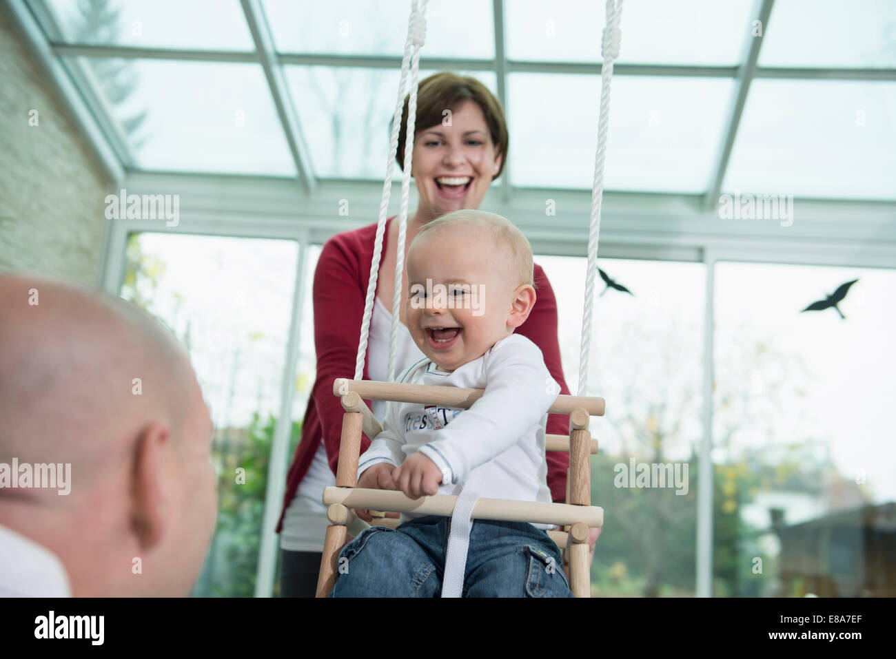 Happy toddler sitting in a swing Stock Photo