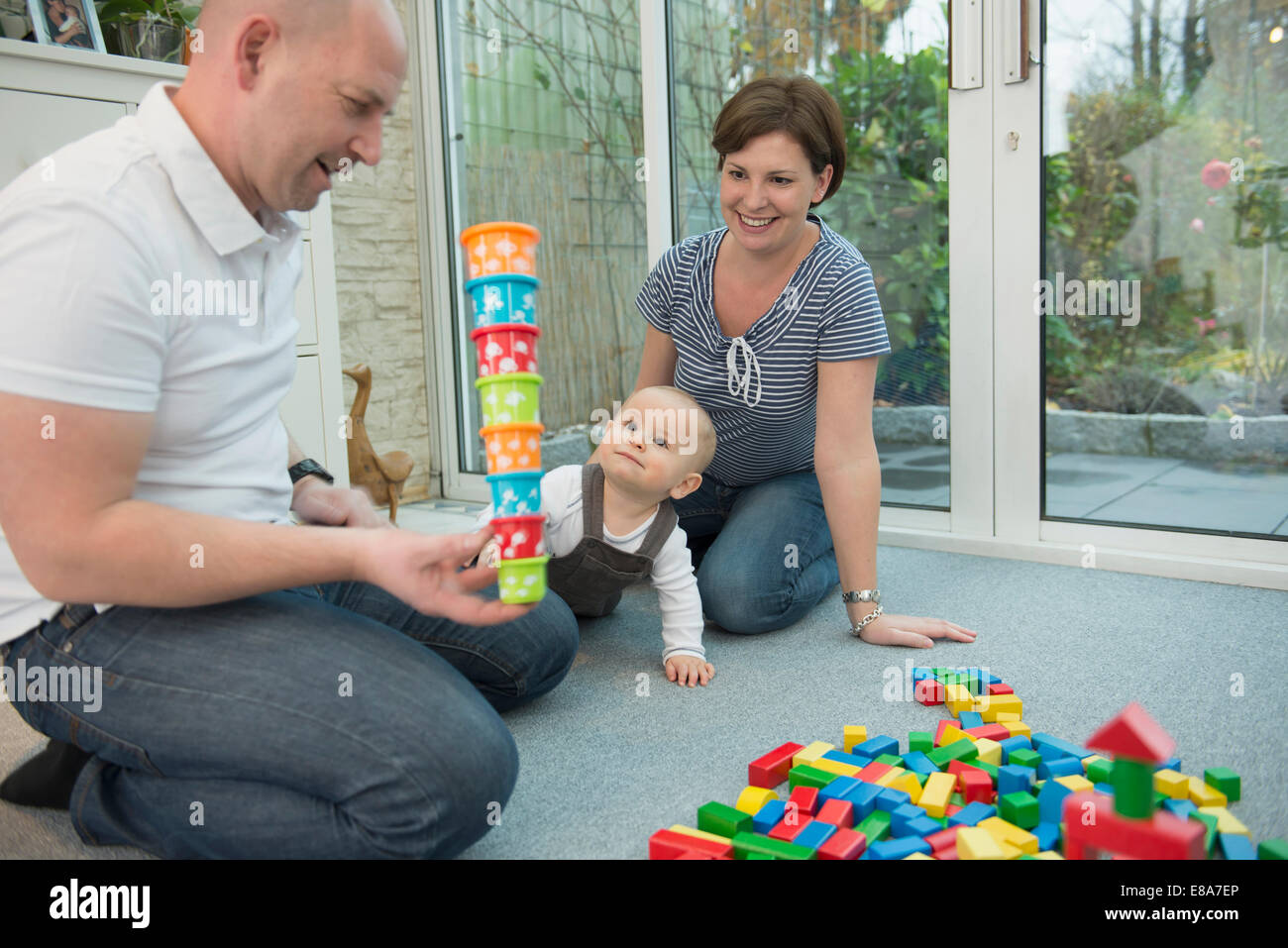 Parents and little son sitting on ground of living room playing together Stock Photo