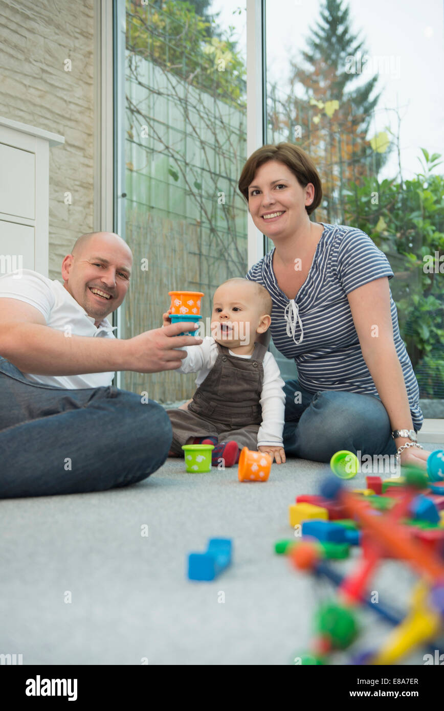 Parents and little son sitting on ground of living room Stock Photo