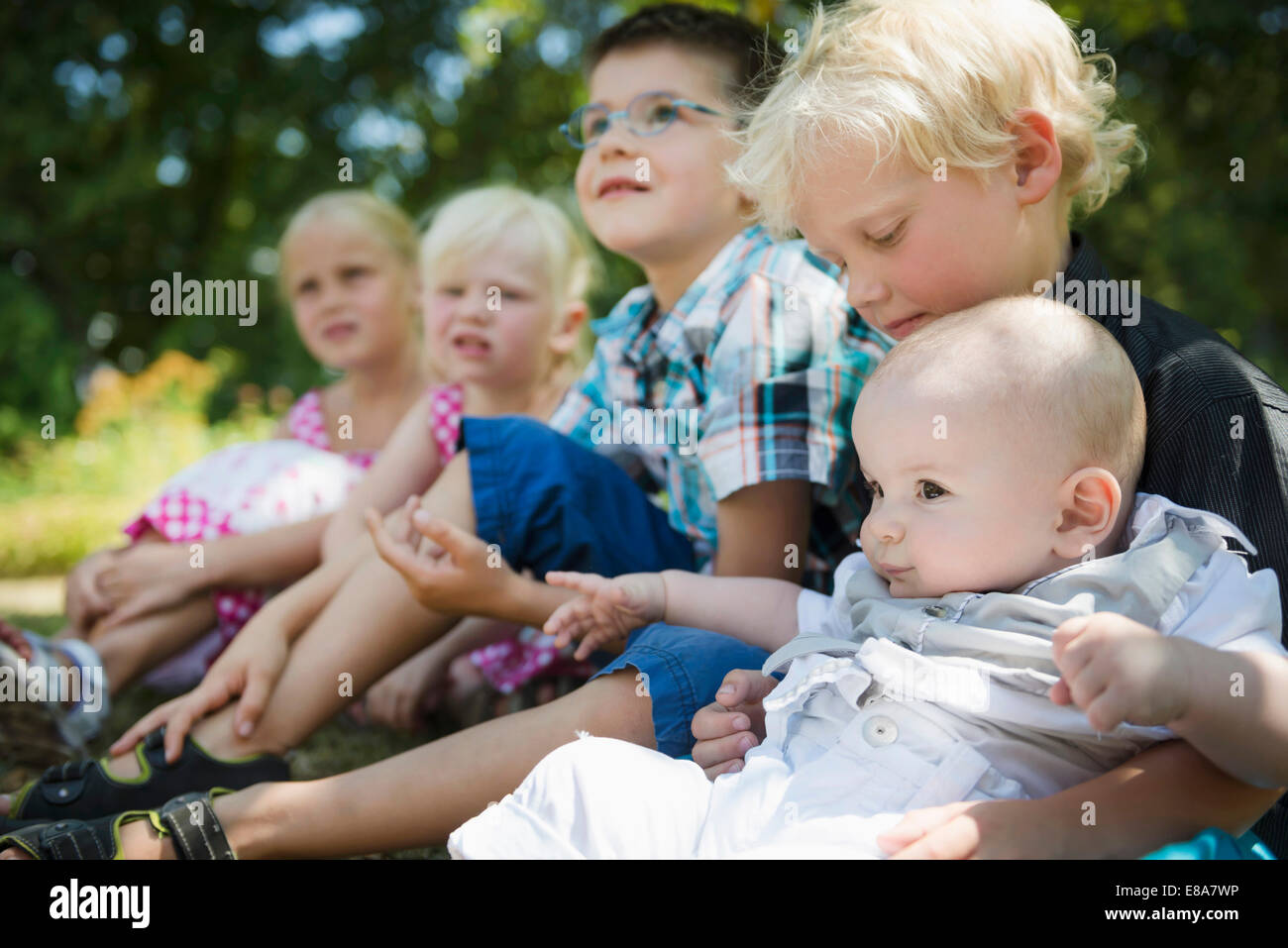 Five children sitting on a meadow Stock Photo - Alamy