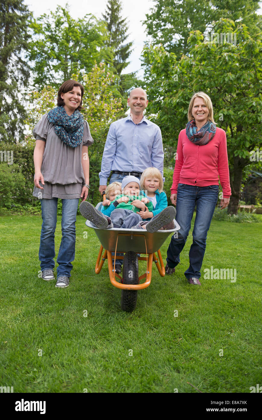 Family garden Father pushing kids wheelbarrow Stock Photo