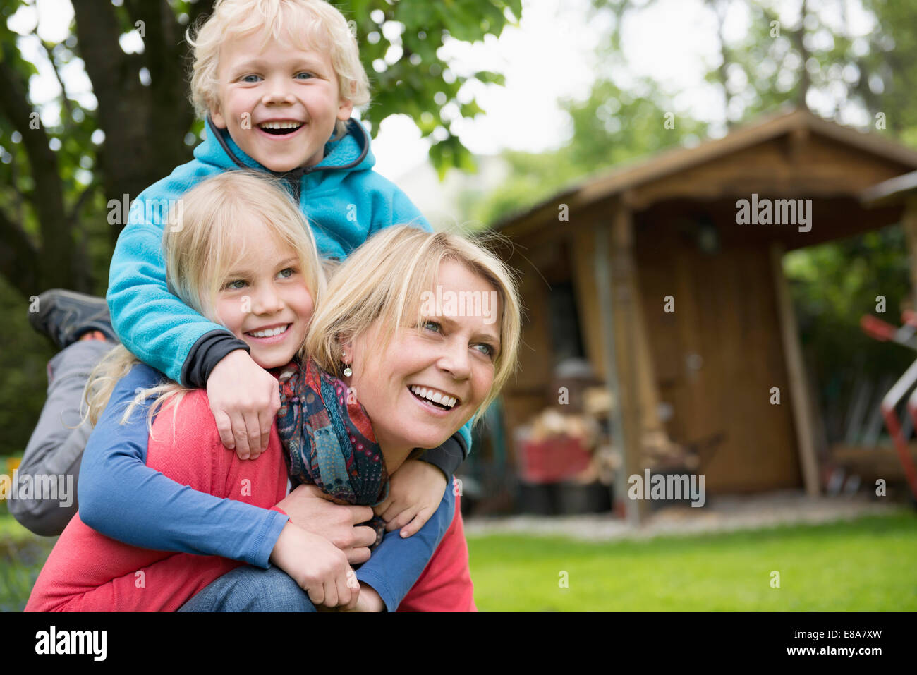 Mother playing garden with young kids piggyback Stock Photo