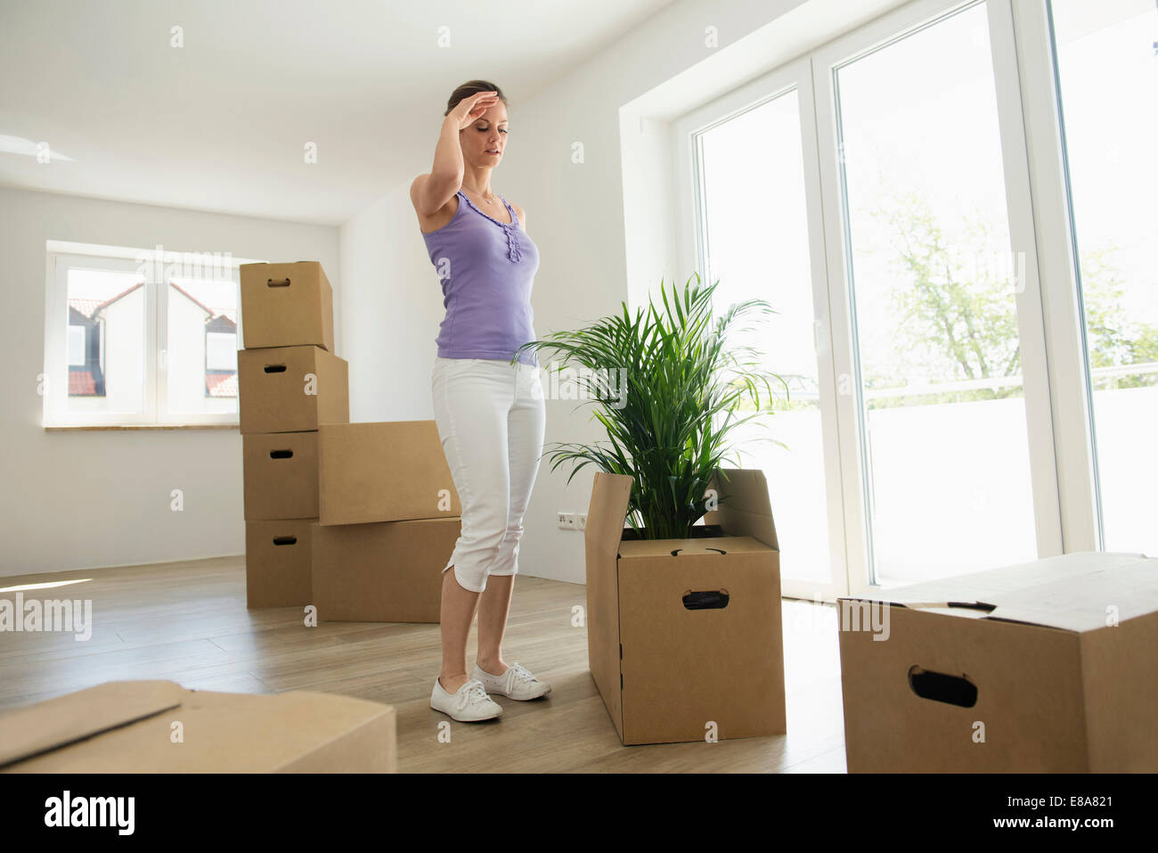 Woman standing tired moving boxes new home Stock Photo