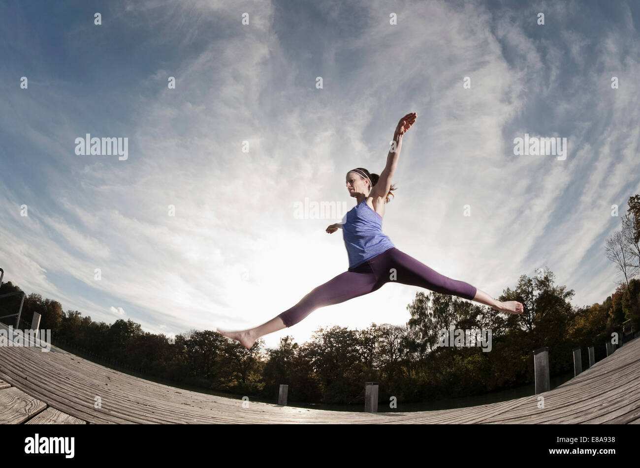 Woman jumpingmid air, Woerthsee, Bavaria, Germany Stock Photo