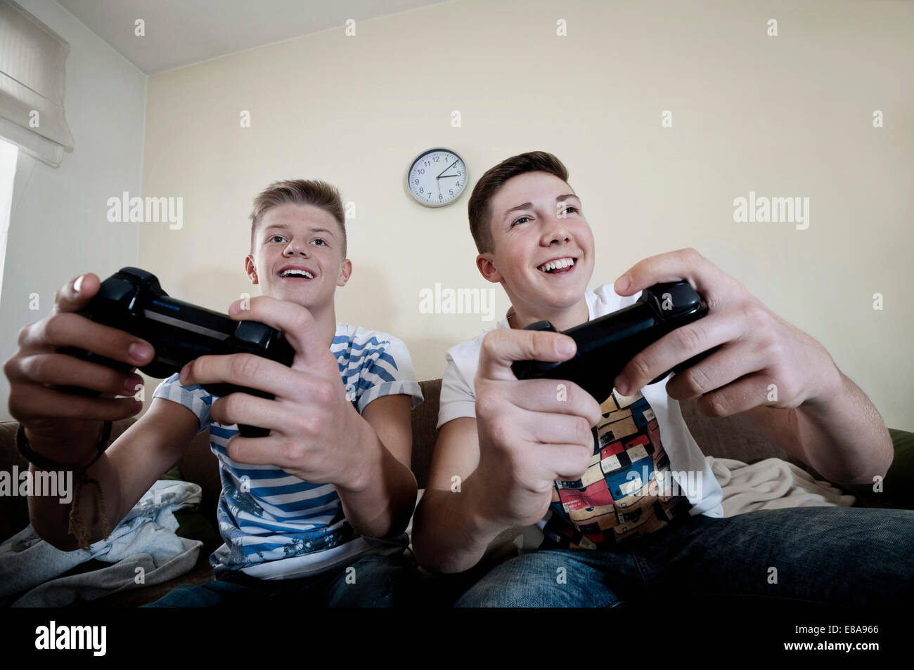 Excited multiethnic teen friends enjoying video games, free time at home, Stock image