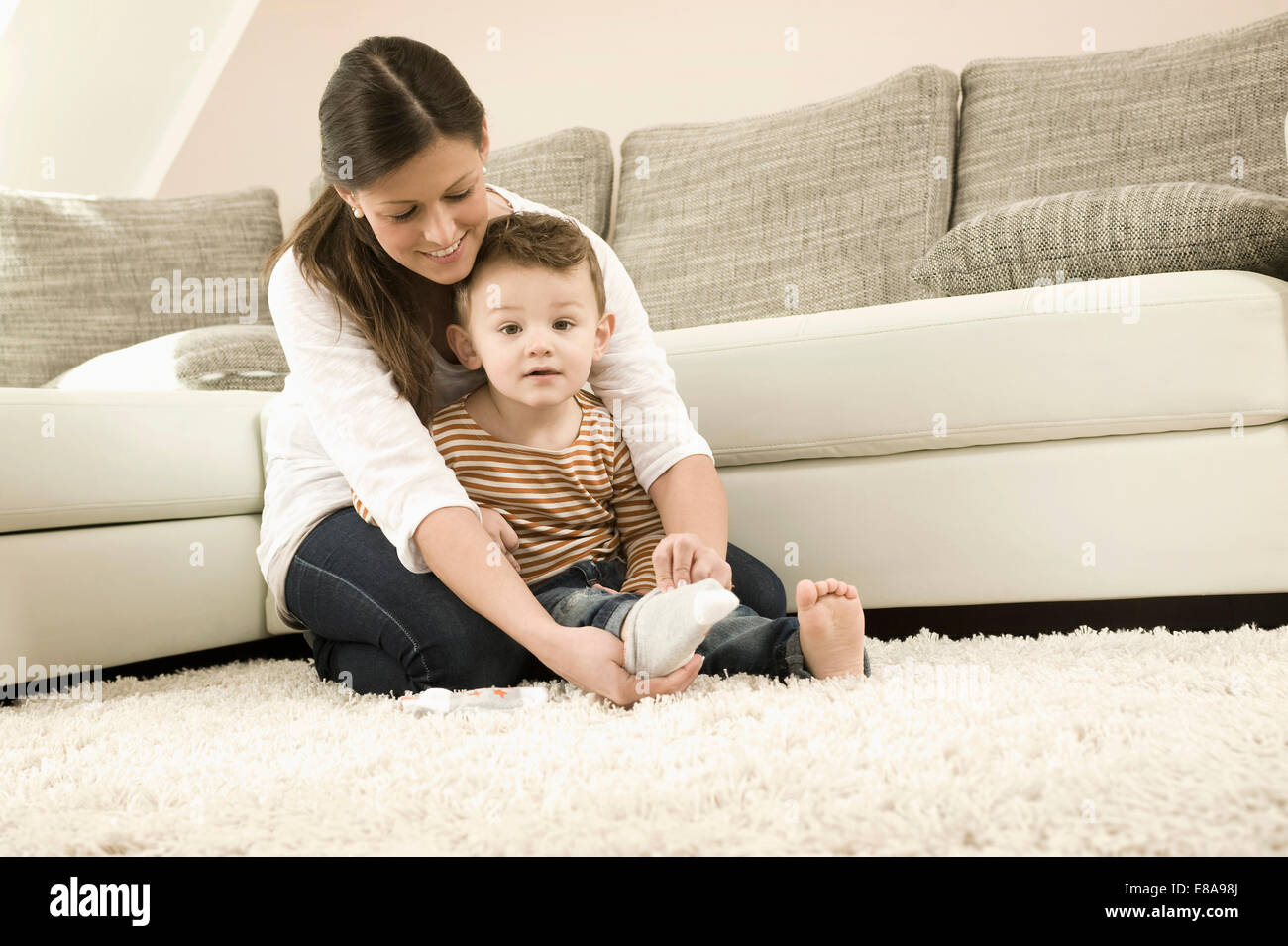 Mother putting socks on son, smiling Stock Photo Alamy