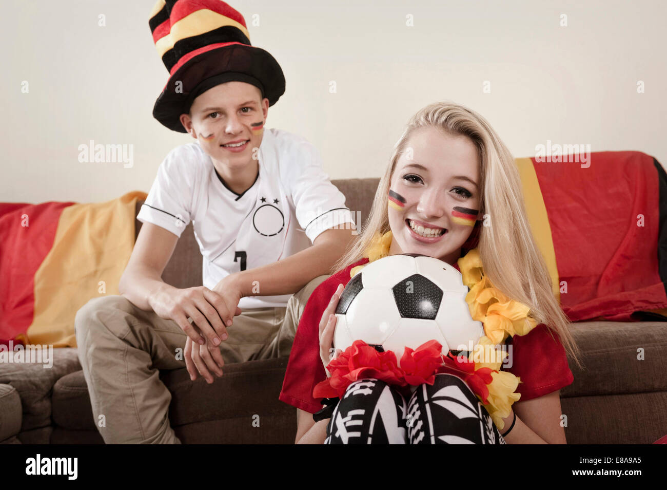 Teenage boy and girl with soccer ball in living room Stock Photo