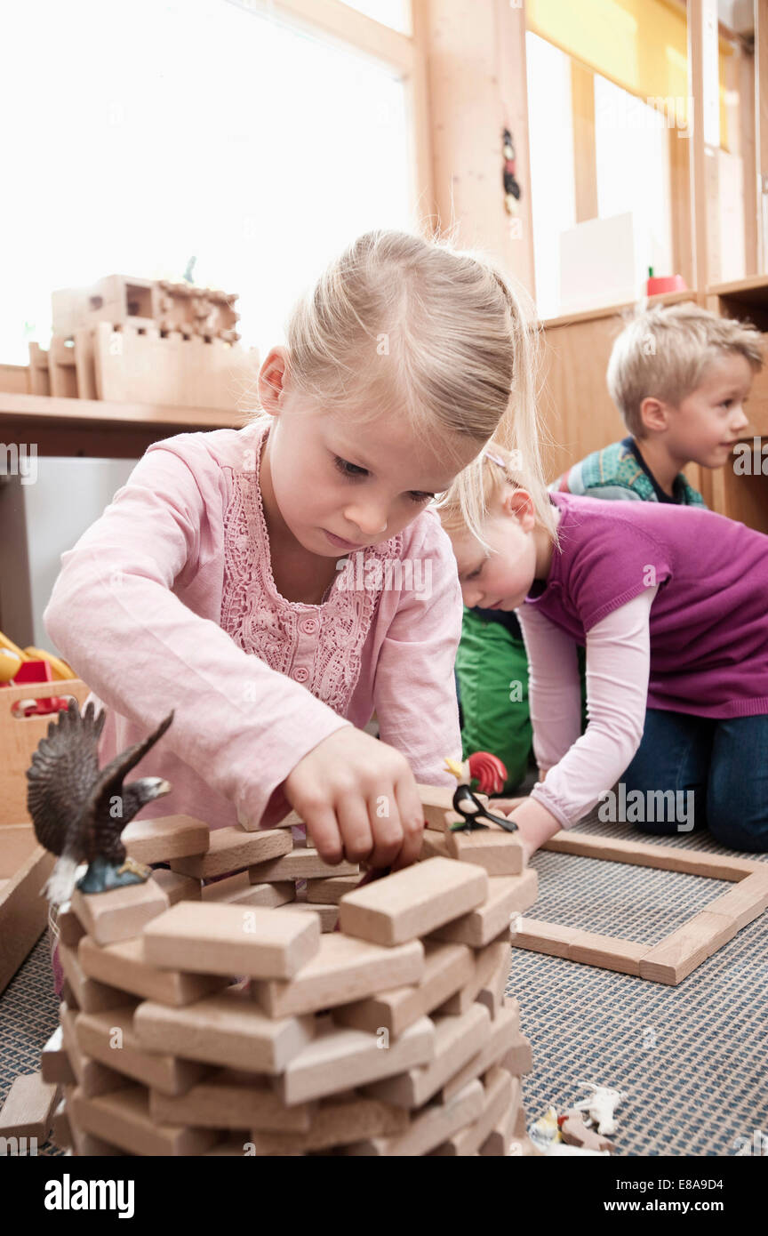 Little Girl Playing With Wooden Building Bricks In Her Kindergarten little-girl-playing-with-wooden-building-bricks-in-her-kindergarten