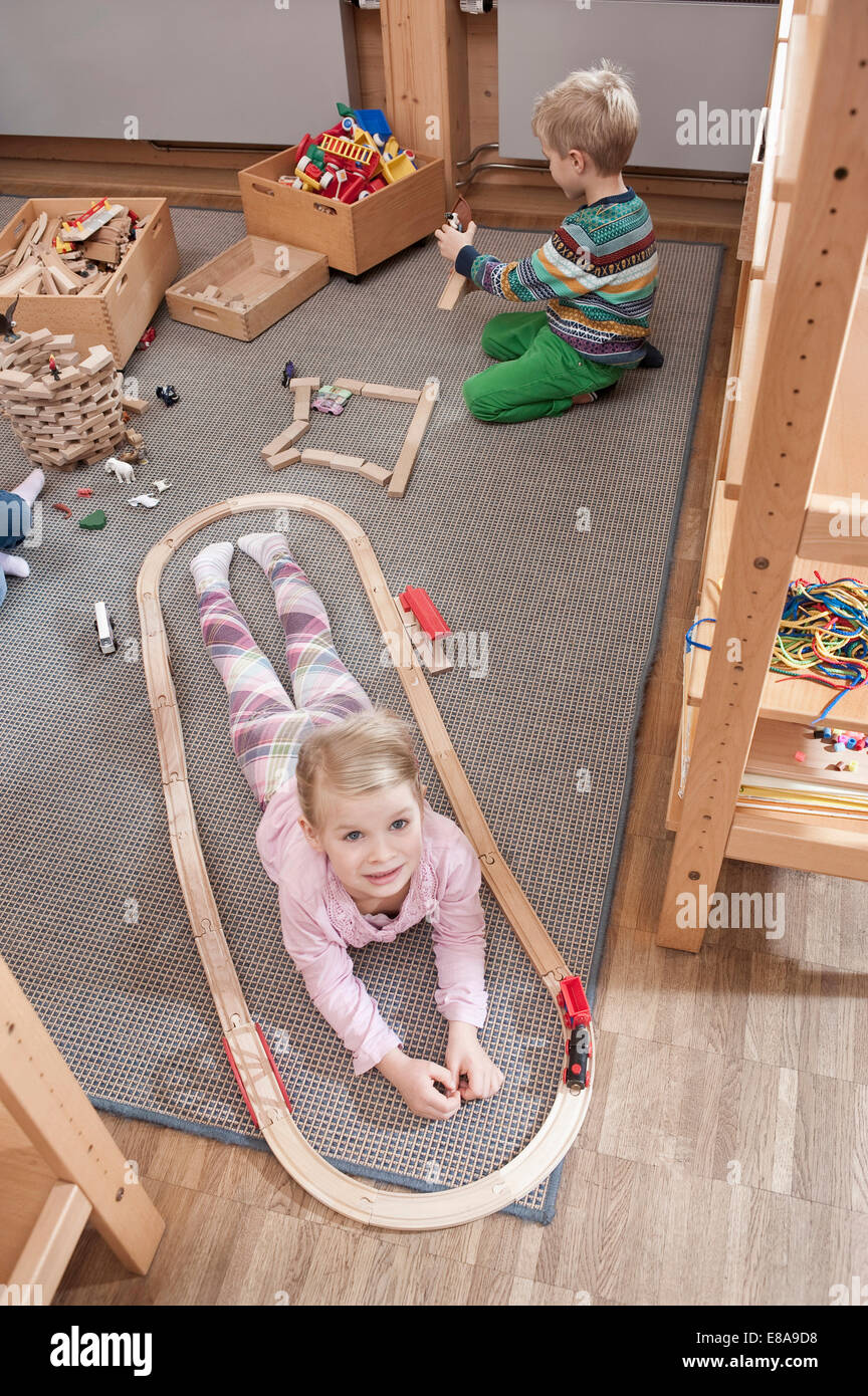 Little girl playing with wooden railroad in her kindergarten Stock Photo