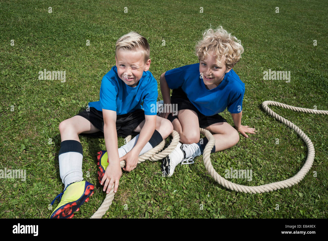 Two young boys resting on grass Tug-of-war Stock Photo
