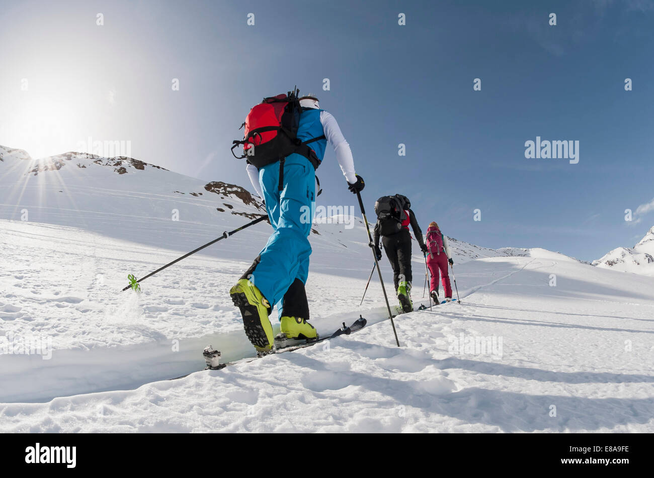 Three skiers climbing steep slope snow winter Stock Photo