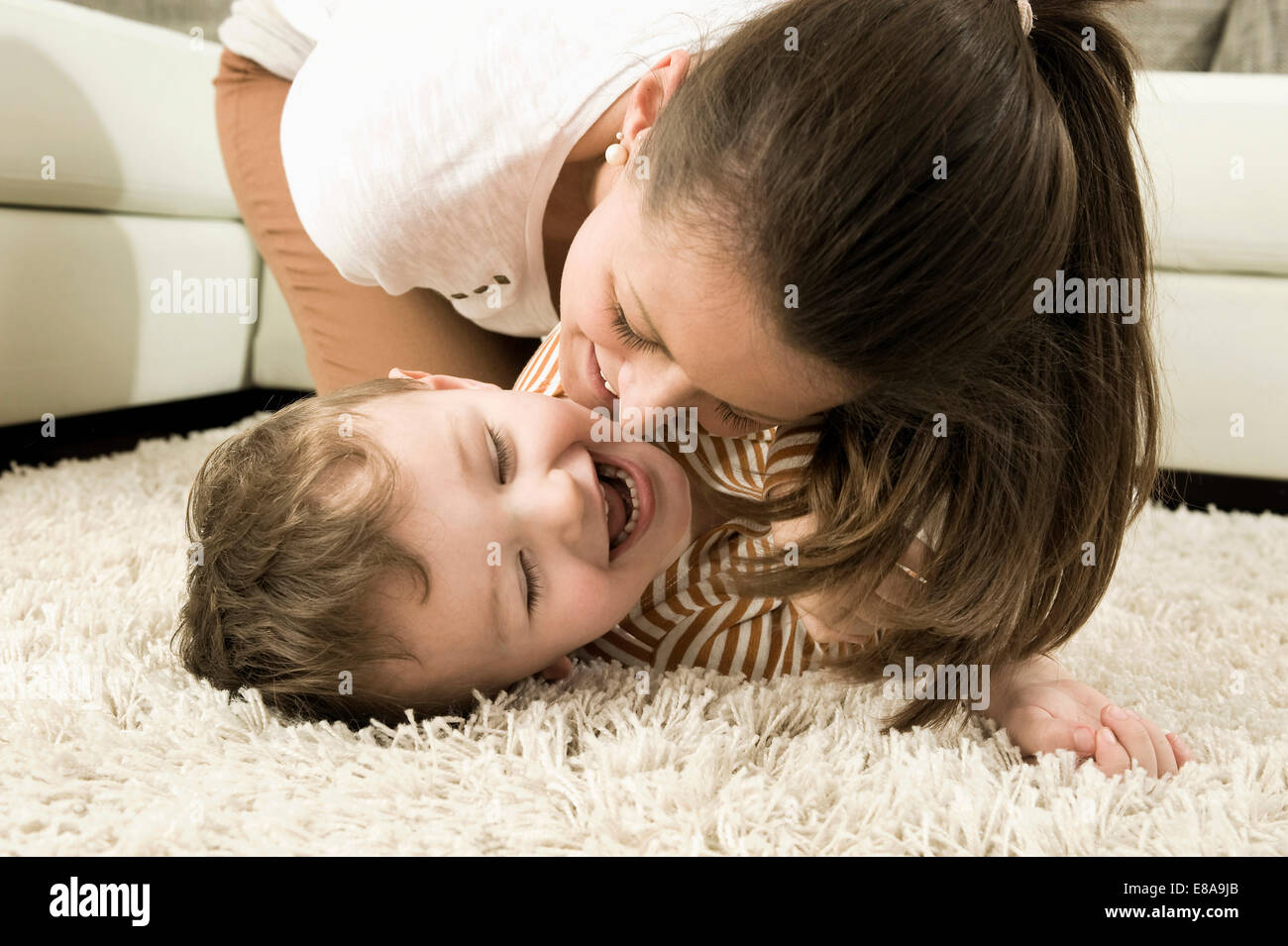 Mother and son are romping in living room, smiling Stock Photo