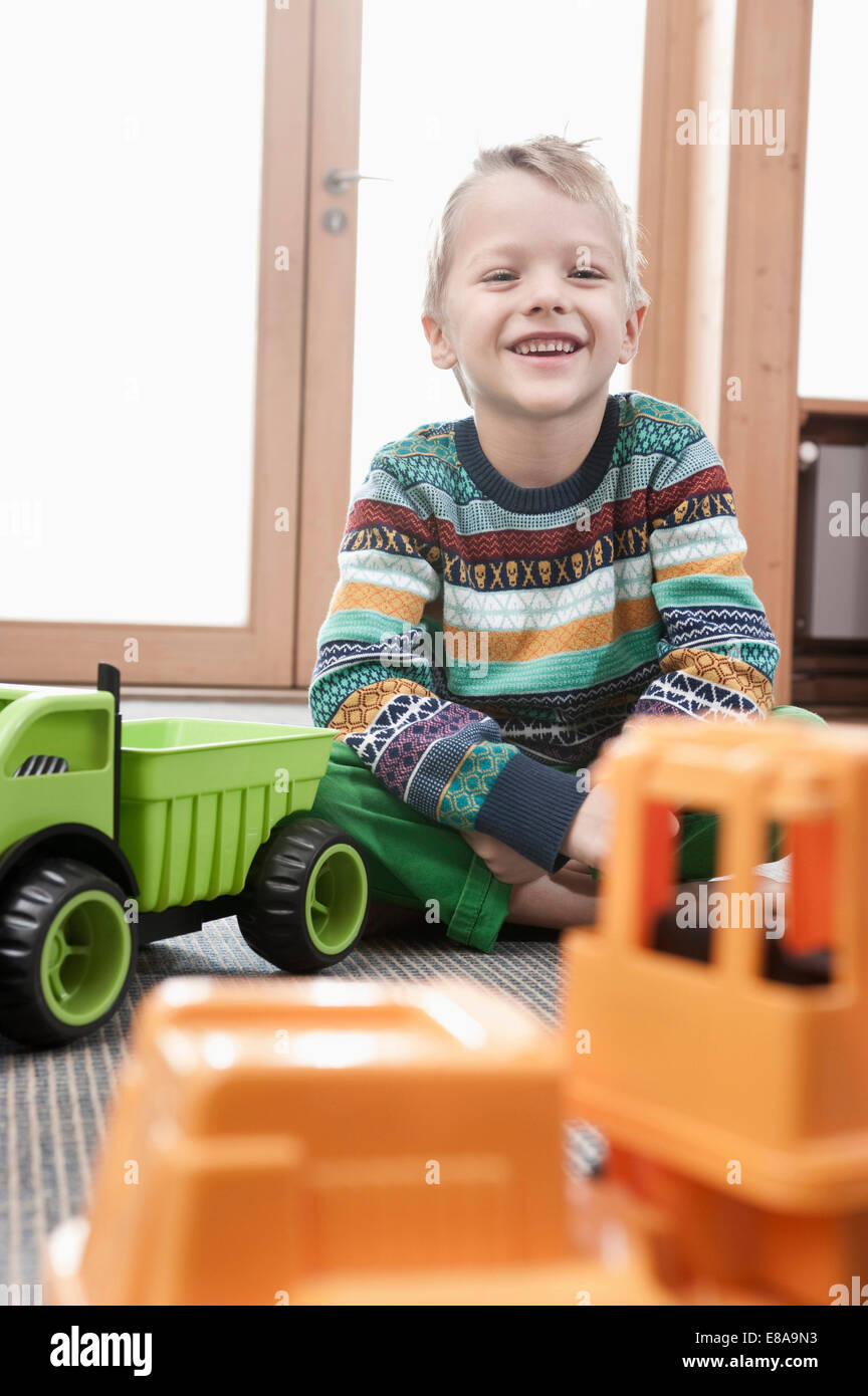Portrait of smiling little boy sitting on ground of his kindergarten Stock Photo