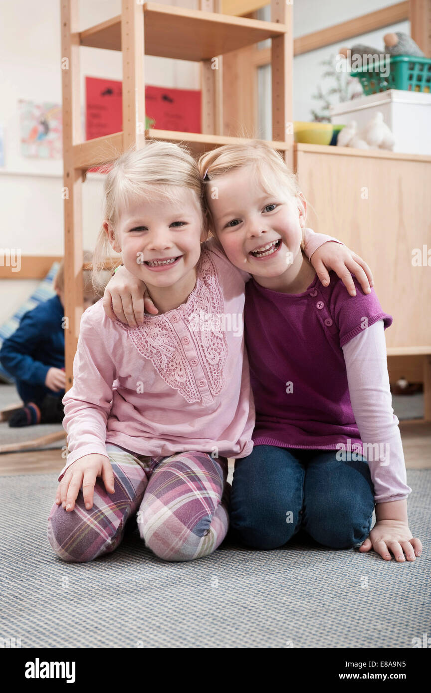 Two Smiling Little Girls Best Friends Sitting On Ground In Kindergarten Two Smiling Little Girls Best Friends Sitting On Ground In Kindergarten