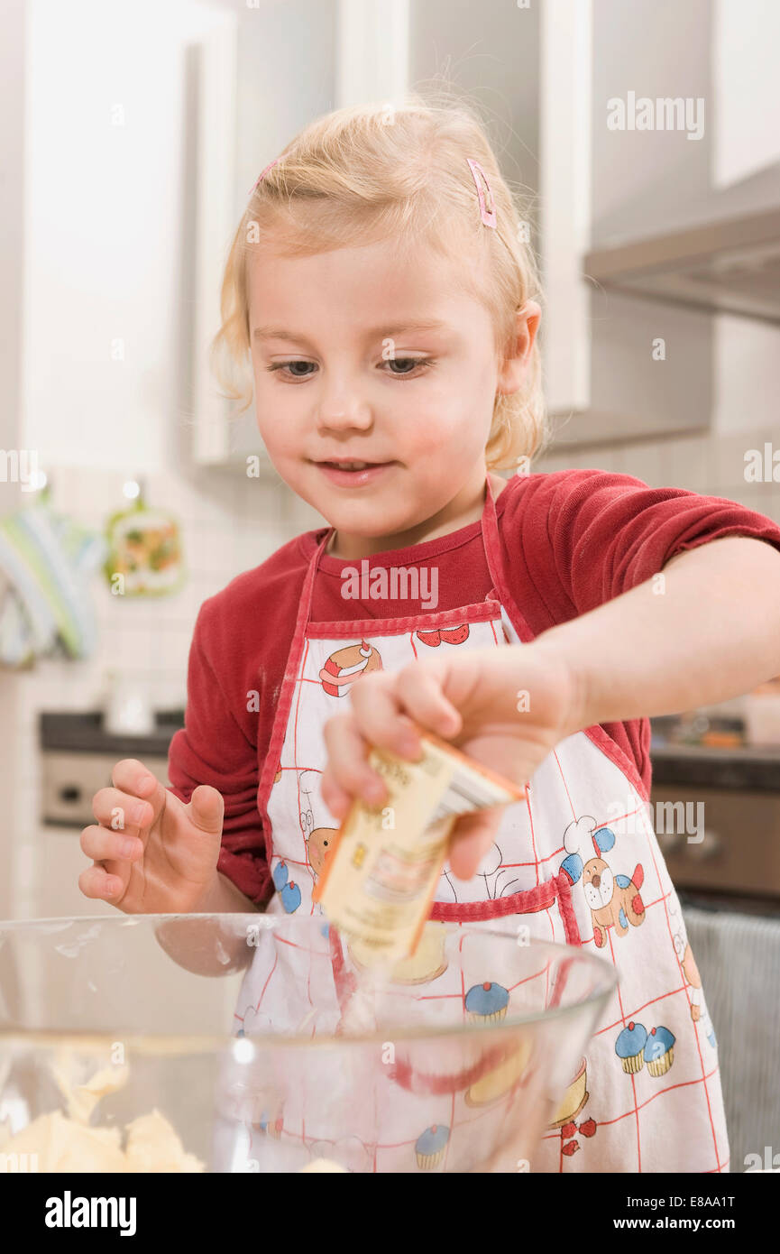Girl pouring baking powder in bowl, smiling Stock Photo Alamy