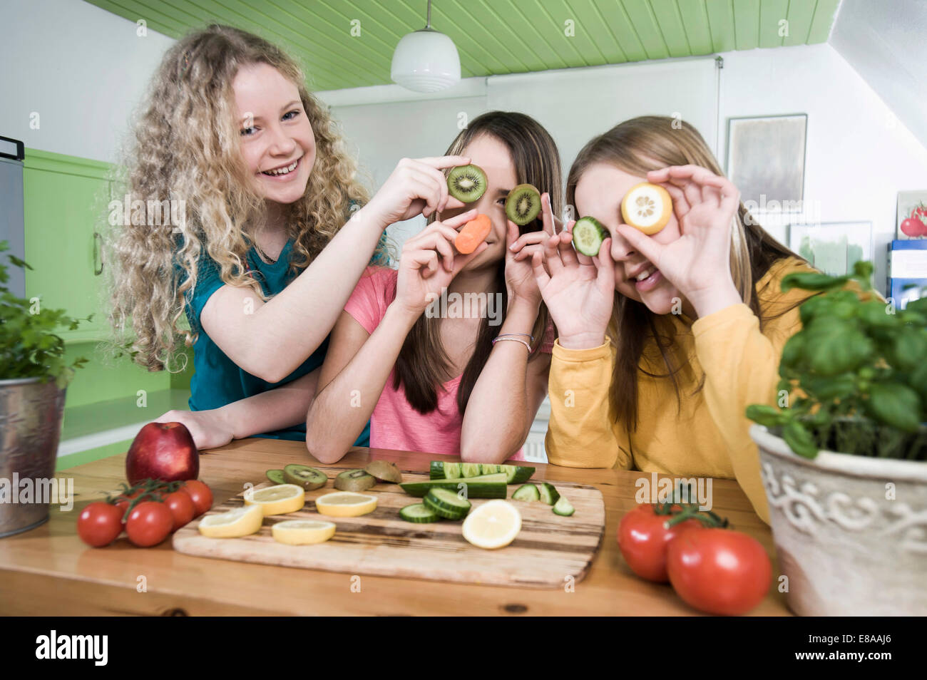 Girls in kitchen making faces with fruit Stock Photo