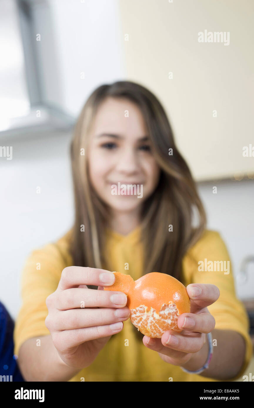 Girl in kitchen peeling mandarine Stock Photo