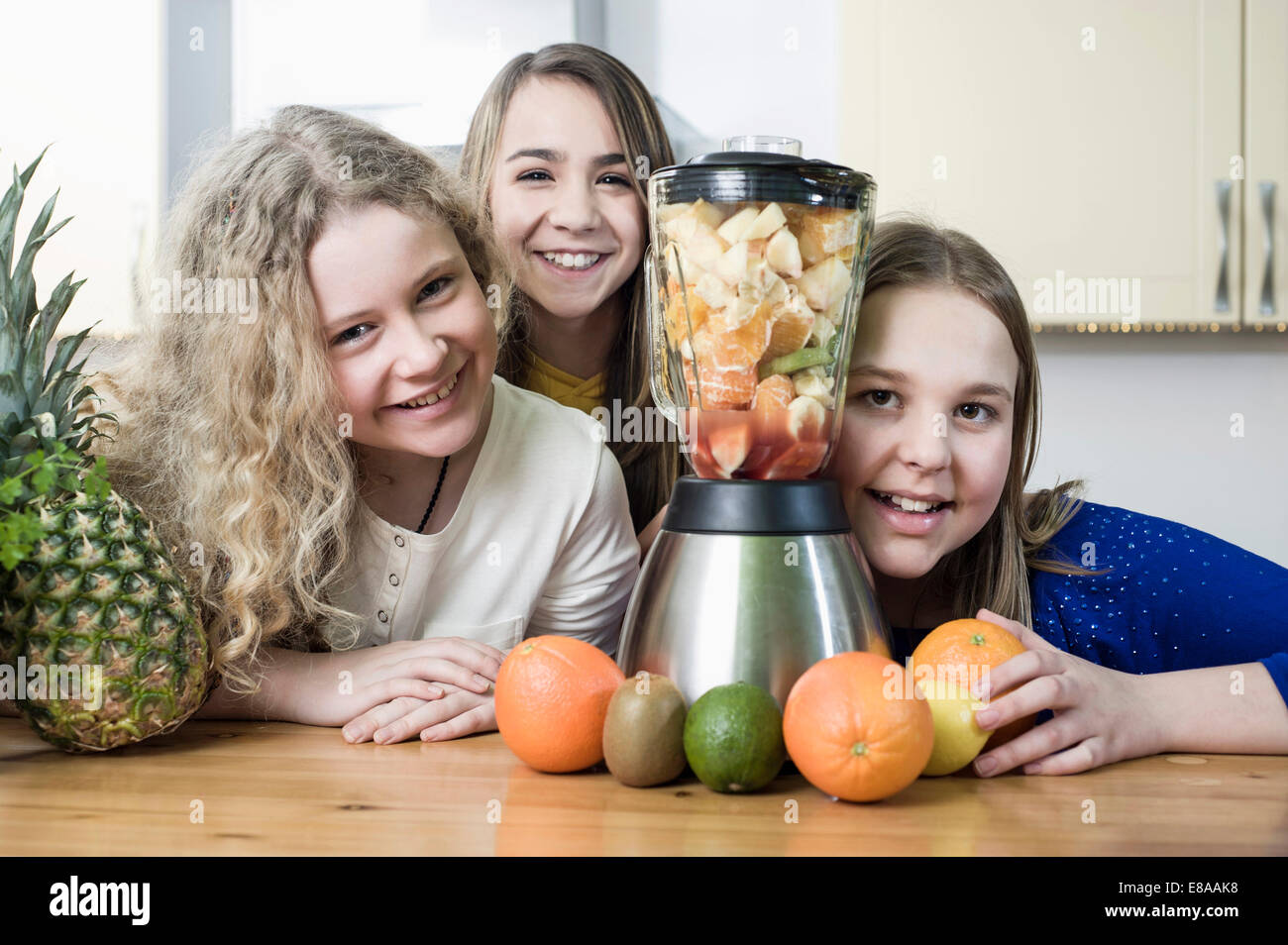 Girls in kitchen preparing fruit smoothie Stock Photo