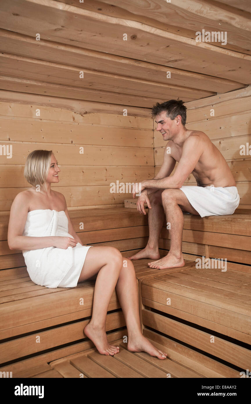 Women Wrapped In Towel Sitting In Sauna Smiling High-Res Stock