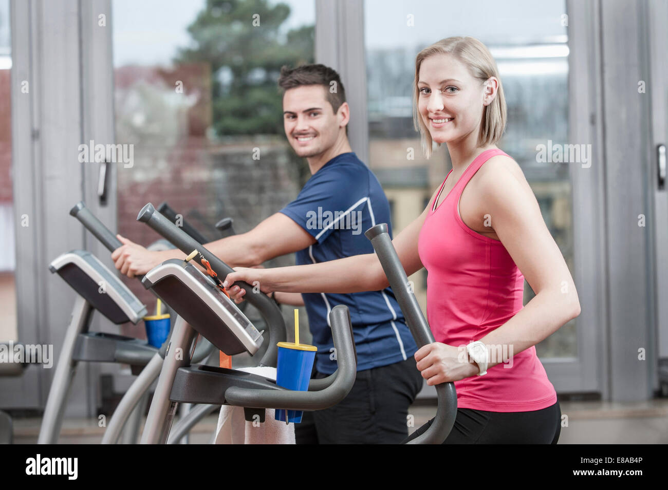 Young man and woman on elliptical trainer in gym Stock Photo - Alamy