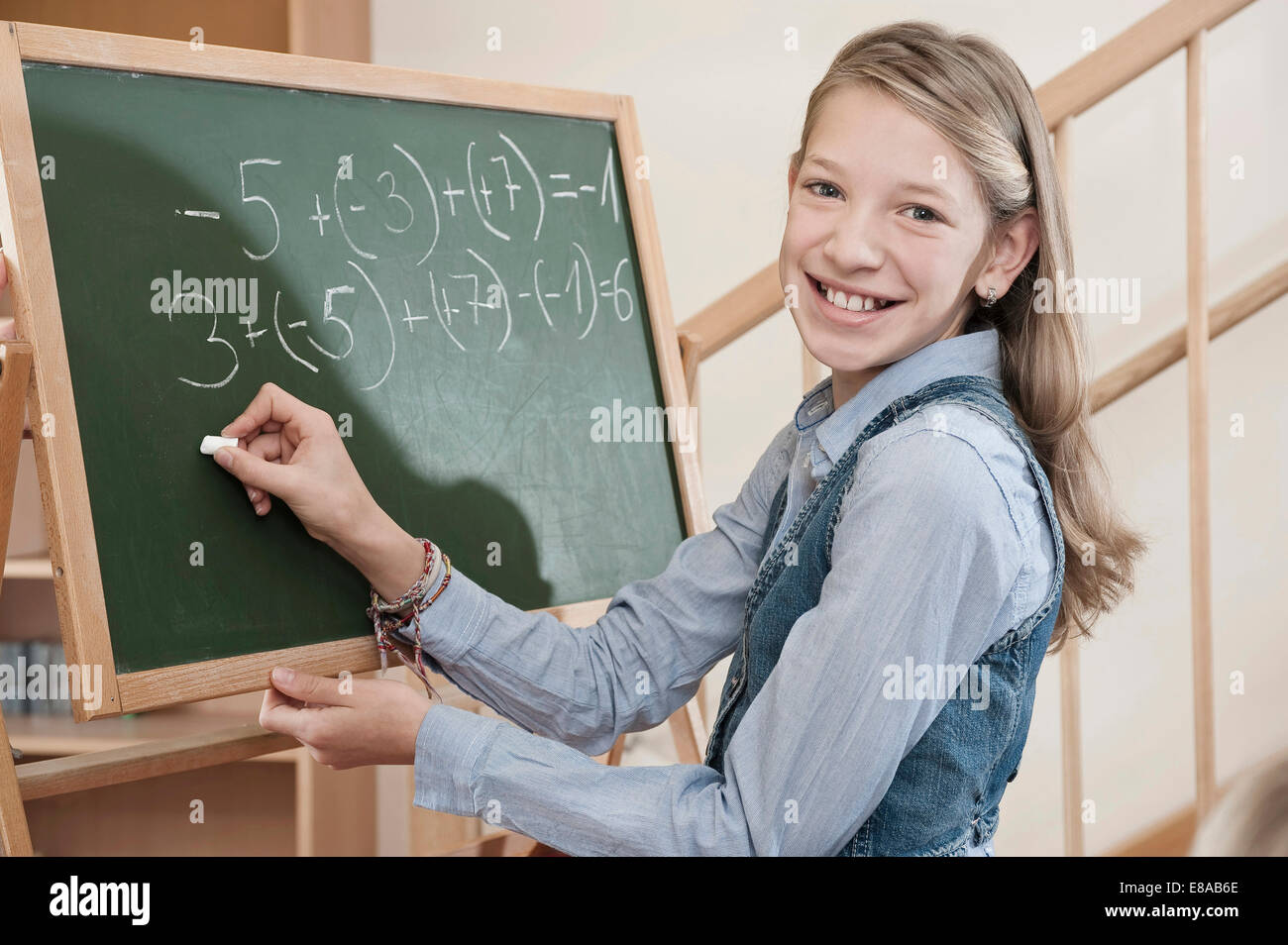 Girl writing arithmetic problem on blackboard Stock Photo