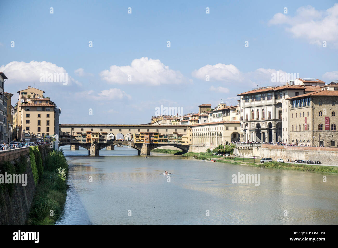 view of Ponte Vecchio bridge with scull on the green Arno river abreast of the water side of the Uffizi Gallery Florence Firenze Stock Photo
