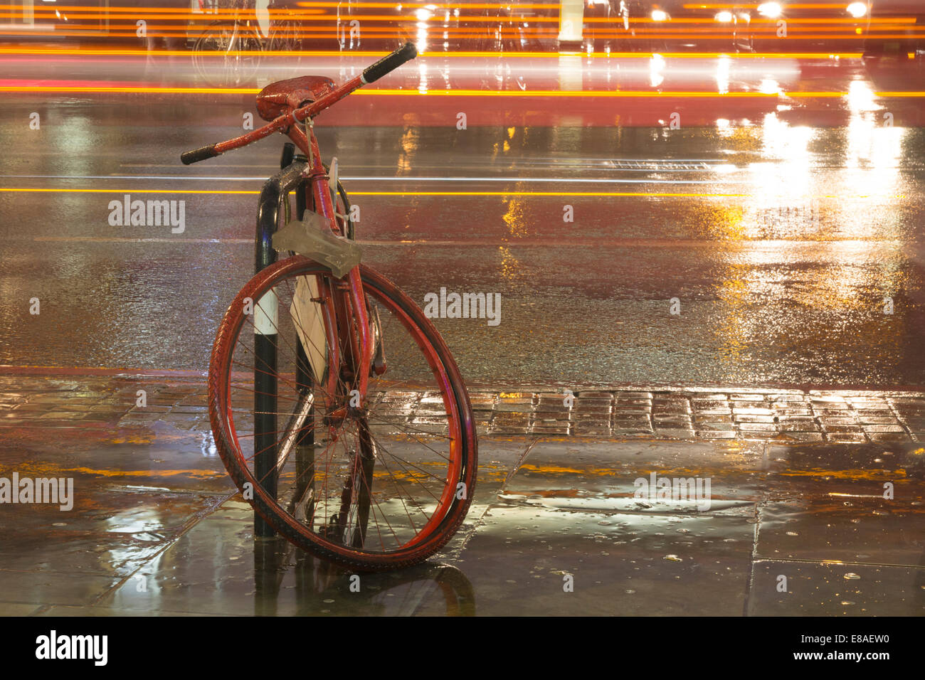 Stationary red bike in the city at night in the rain Stock Photo Alamy