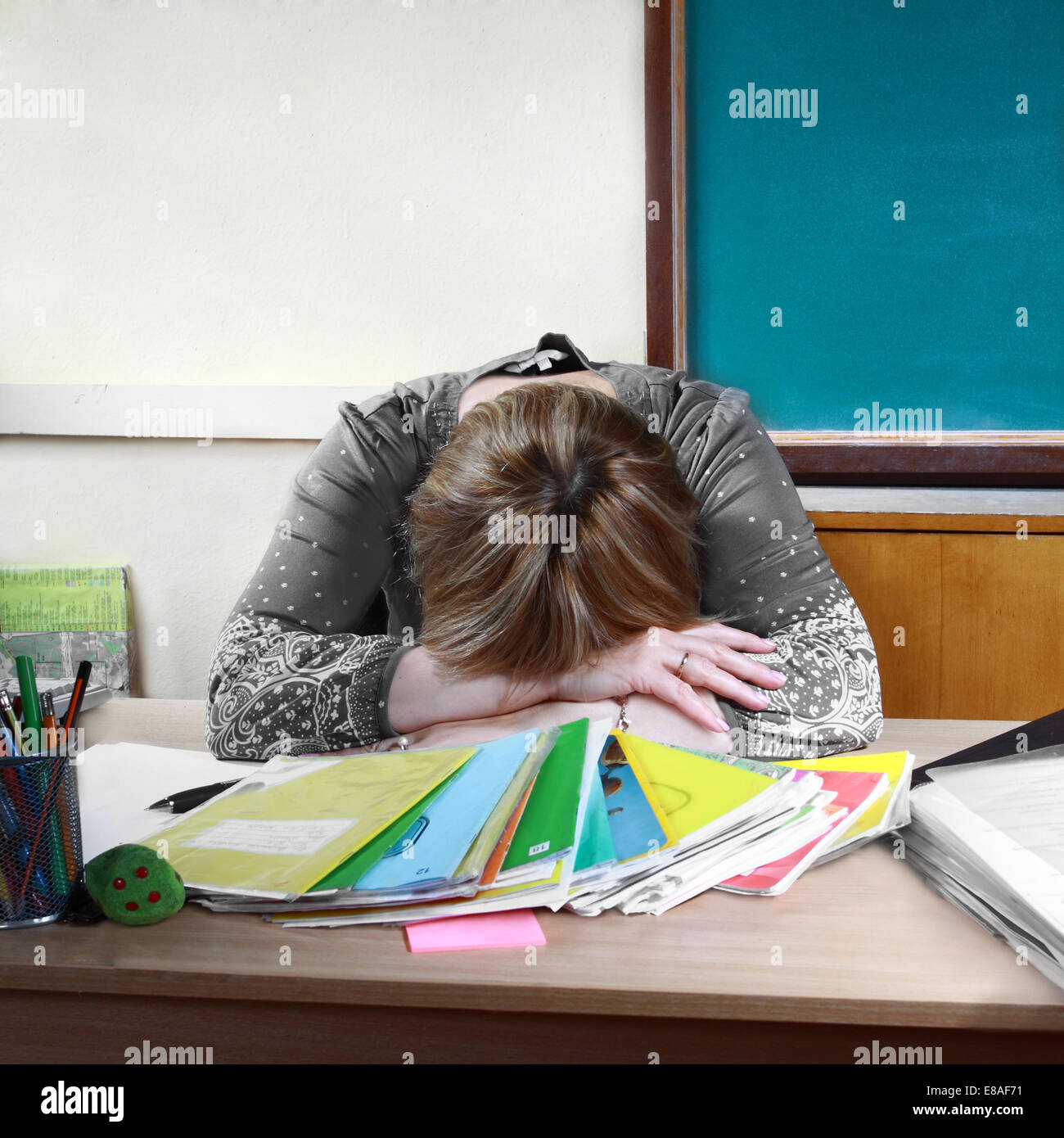 Teacher sits in classroom setting head on hands Stock Photo