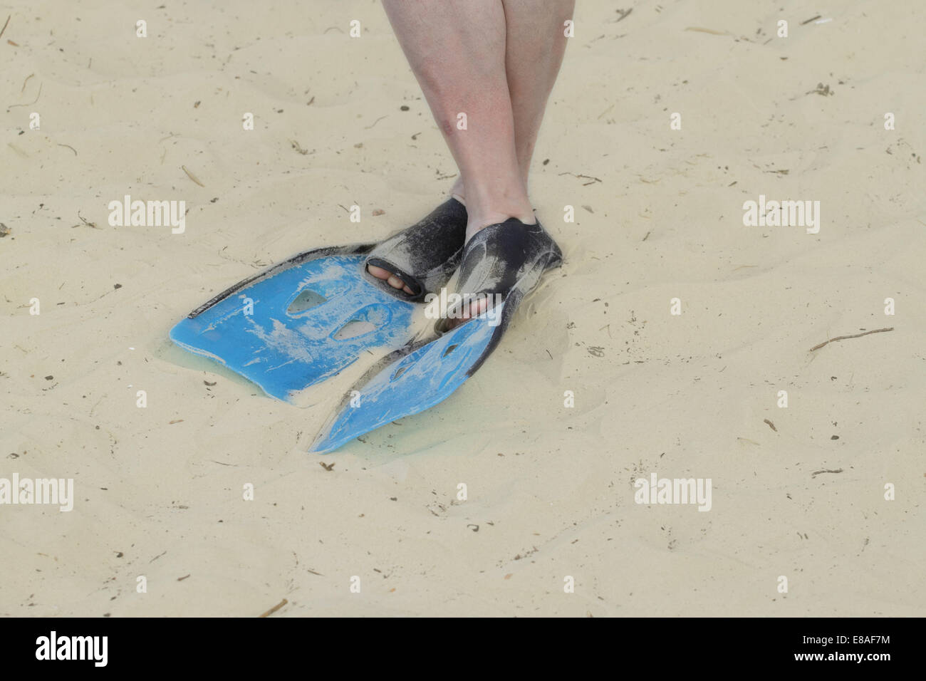 Crossed legs in flippers on sand closeup Stock Photo