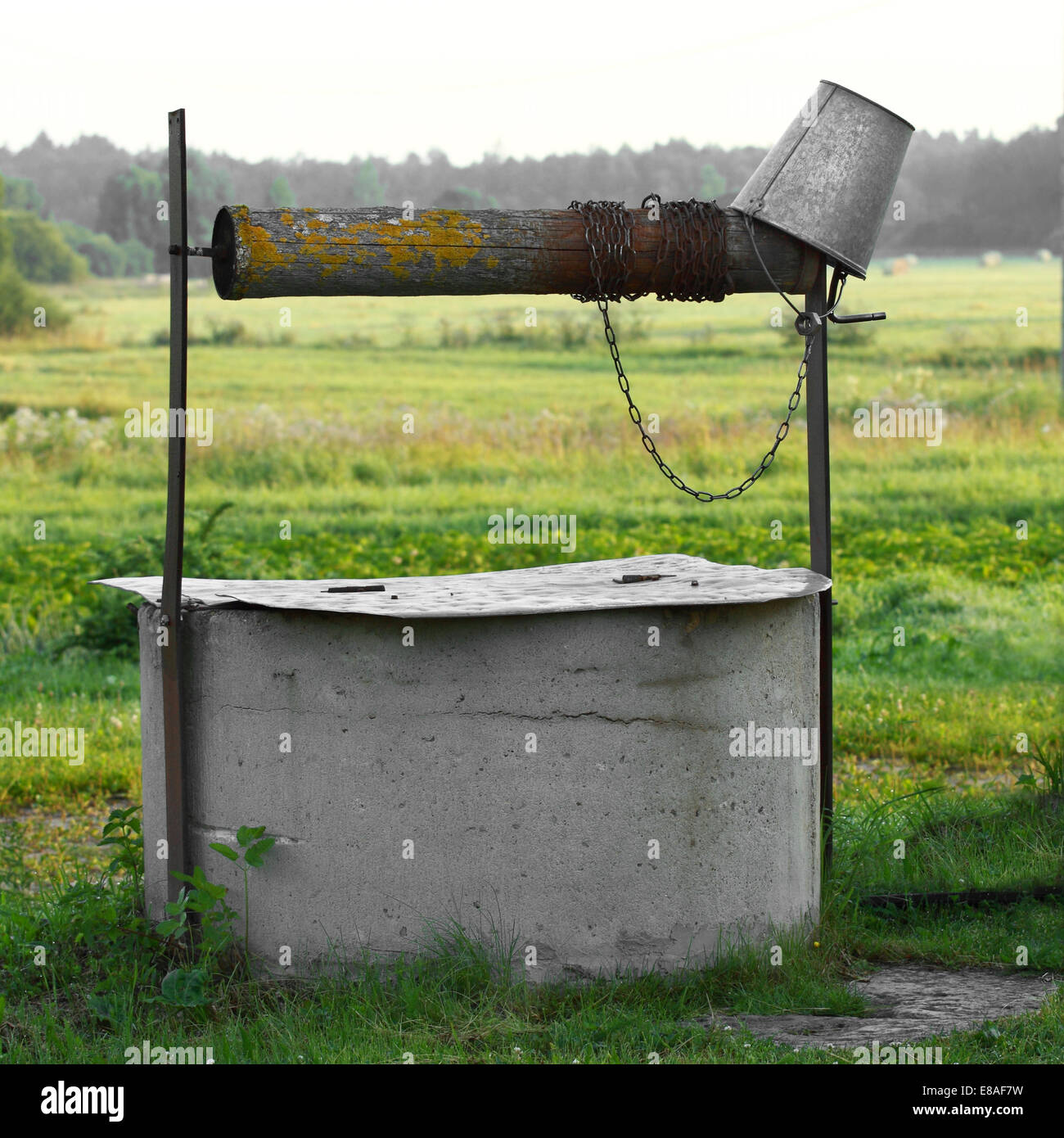 Concrete well with tin bucket on natural country background Stock Photo