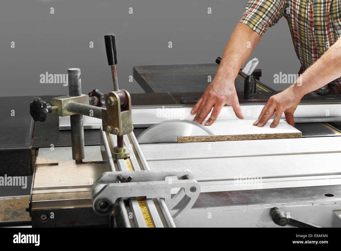 Hands of master cutting the board on rotating saw blade Stock Photo