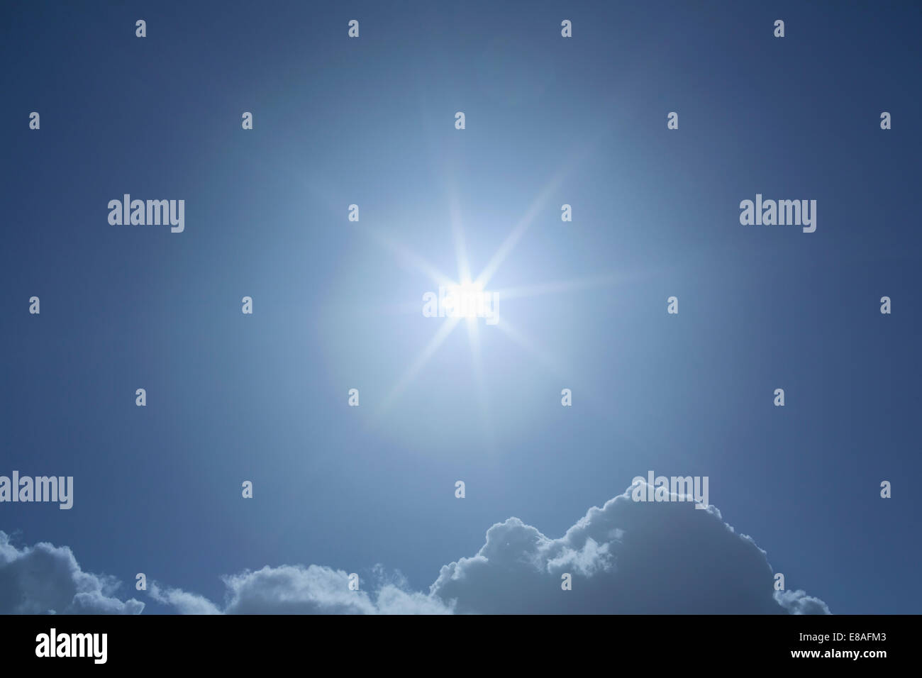 sunburst in blue sky above clouds Stock Photo
