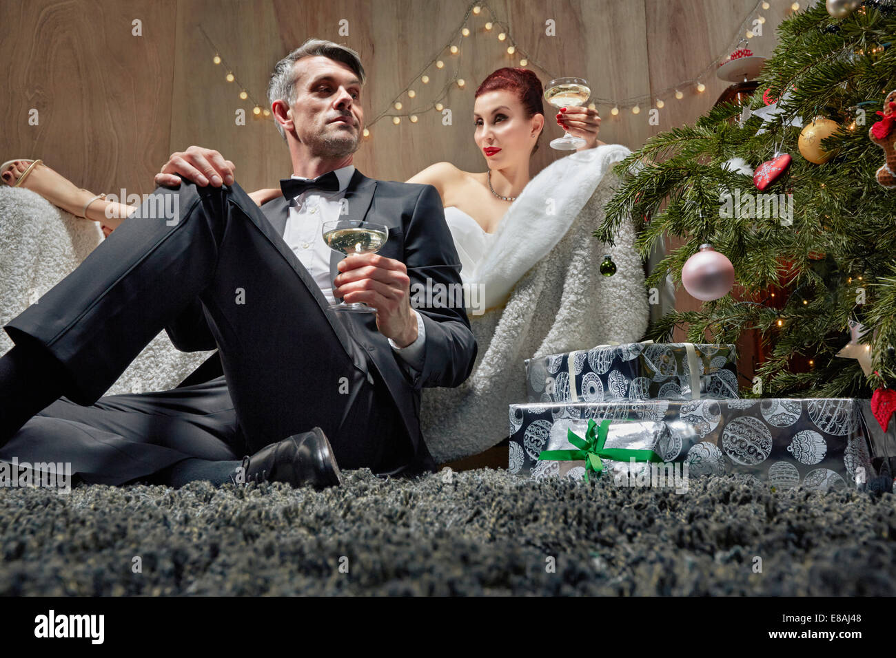 Husband and wife lounging by Christmas tree Stock Photo