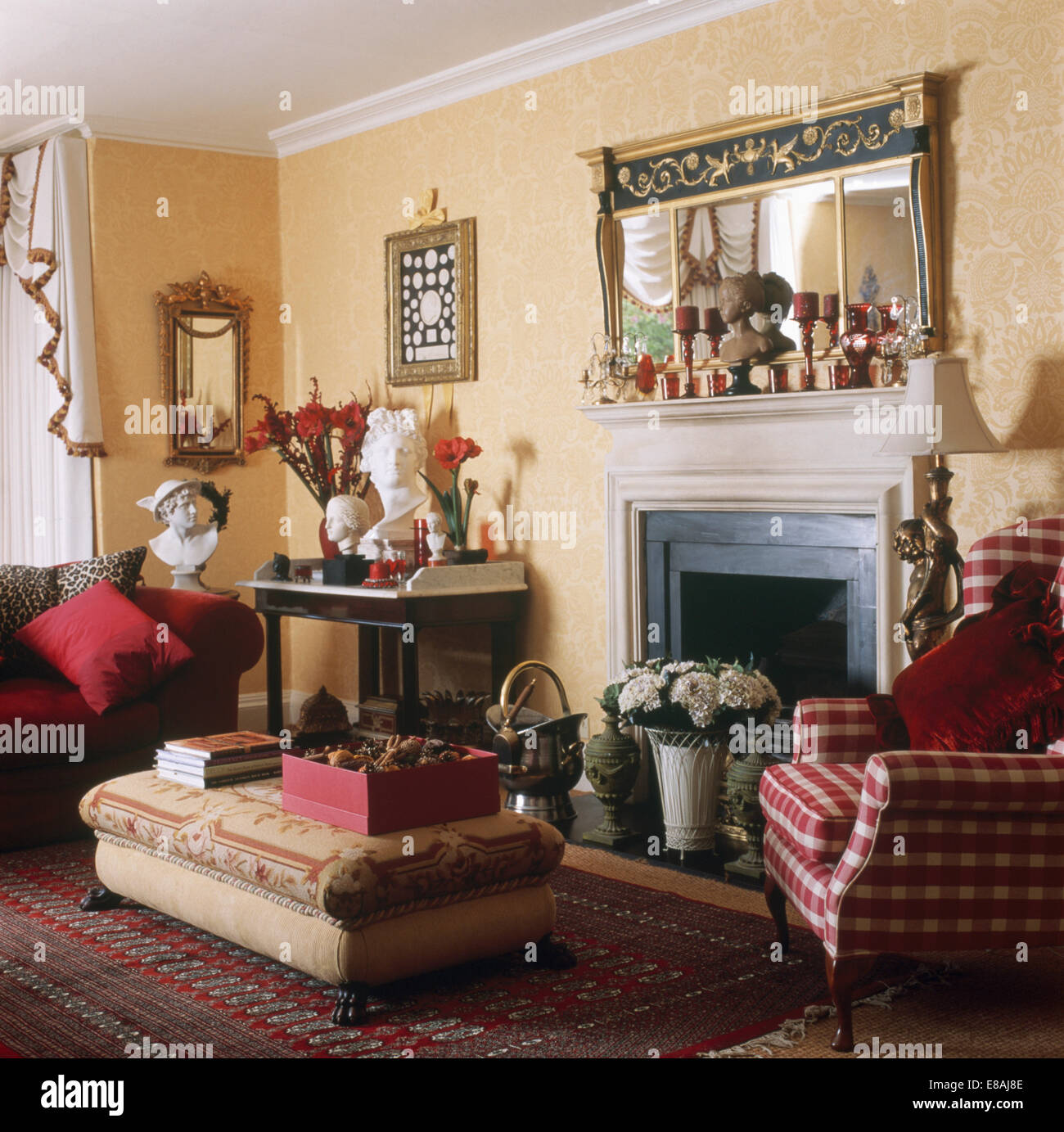Ottoman and red checked armchair beside fireplace with pot of white