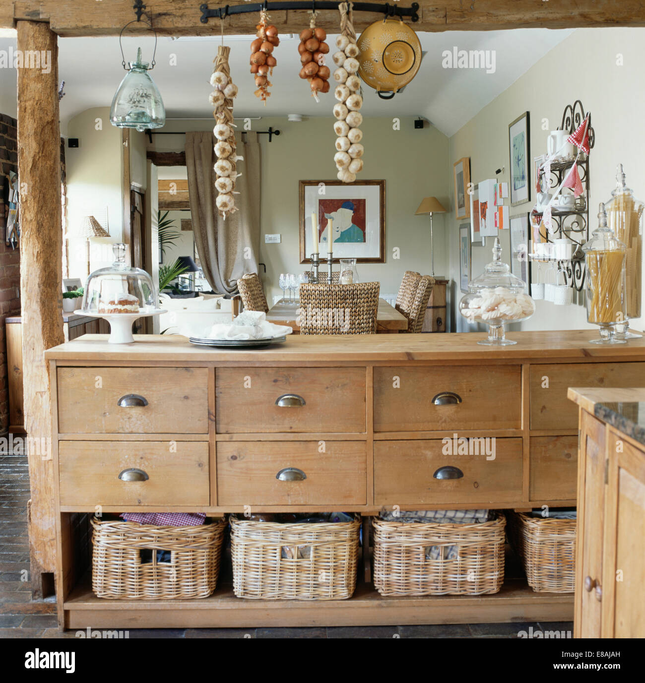 Storage baskets on old pine cupboard dividing cottage kitchen and