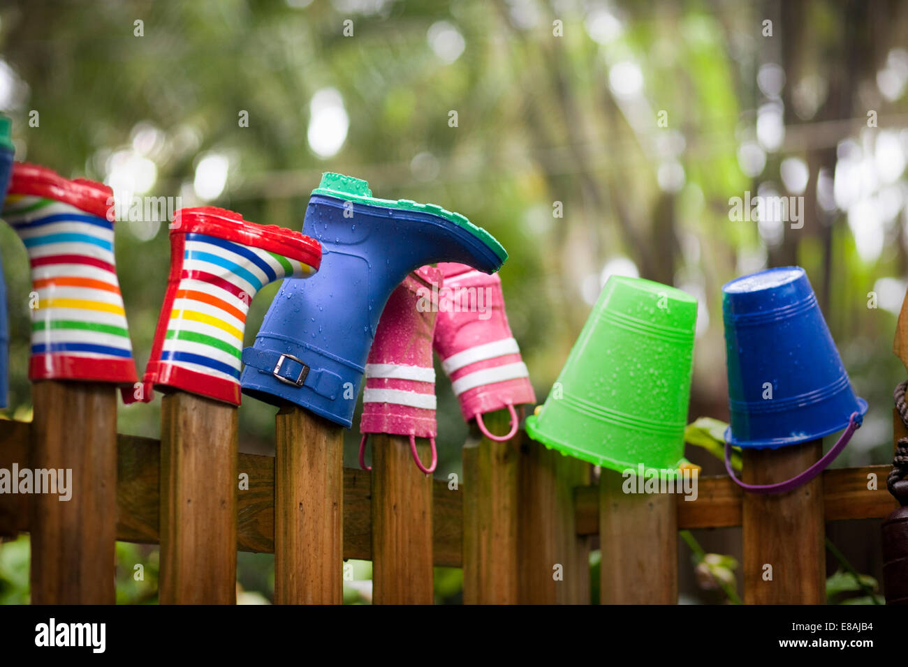 Row of rubber boots and buckets on top of garden fence Stock Photo